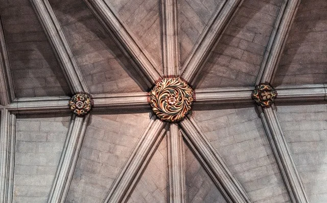 Ceiling with decorative ribbed vaulting and ornate central boss in Gothic architectural style.