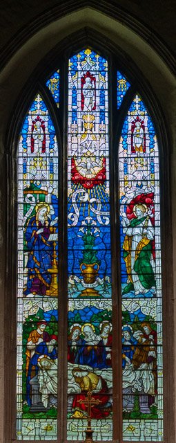 Colorful stained glass window with religious scenes and figures in a church.