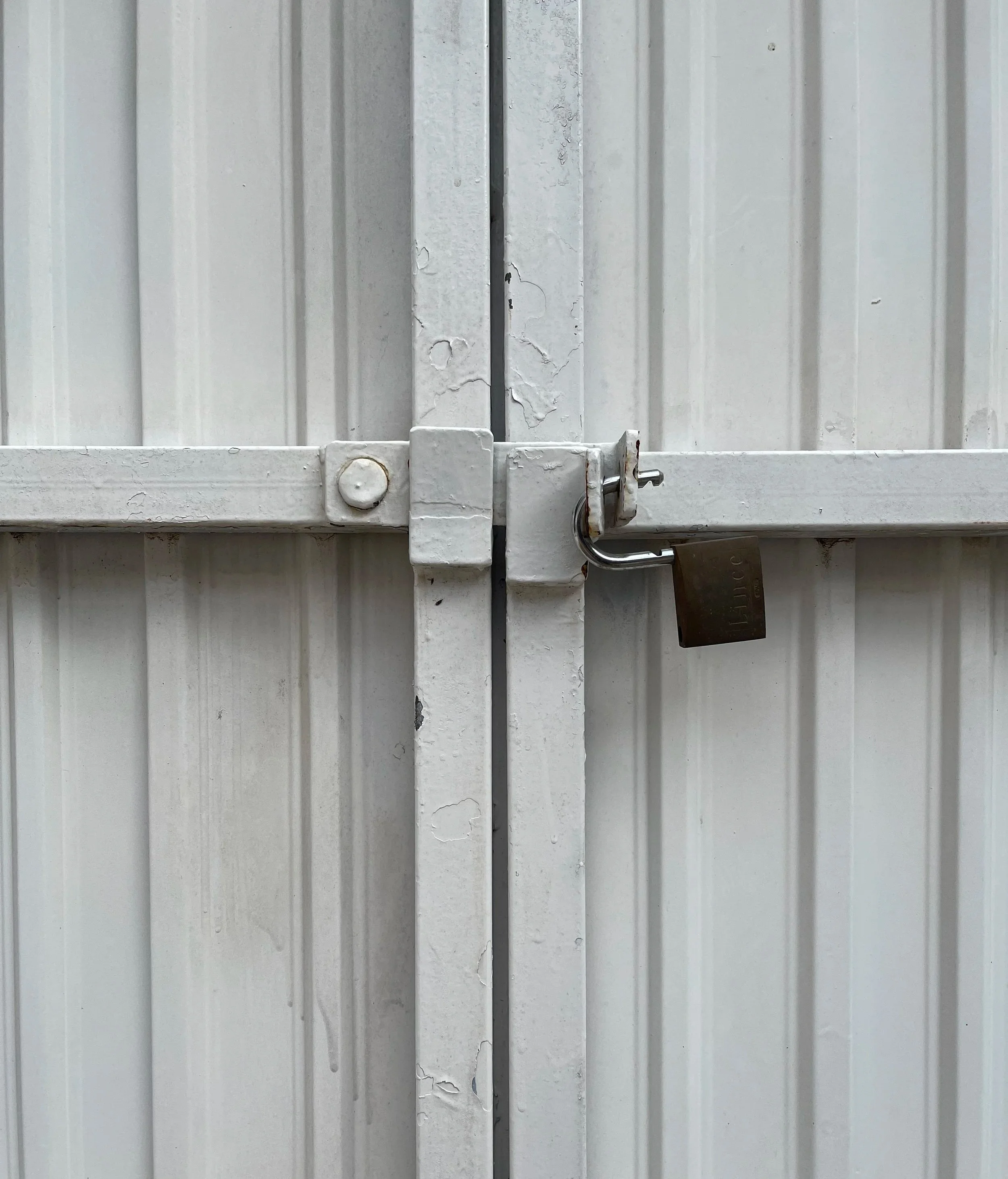 White metal gate with a padlock and latch.