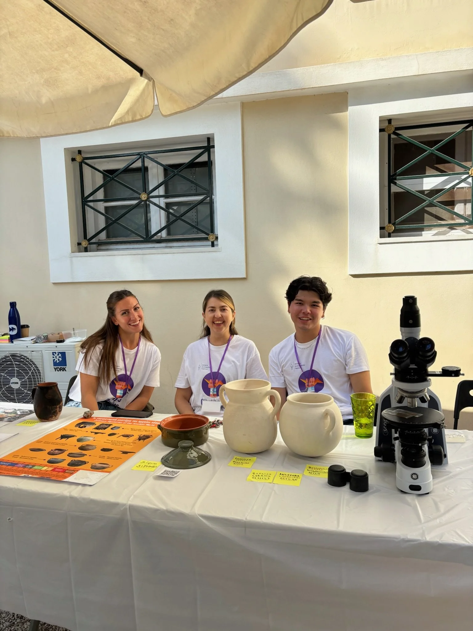 Three activity leaders sat at a table with cooking pots and microsope