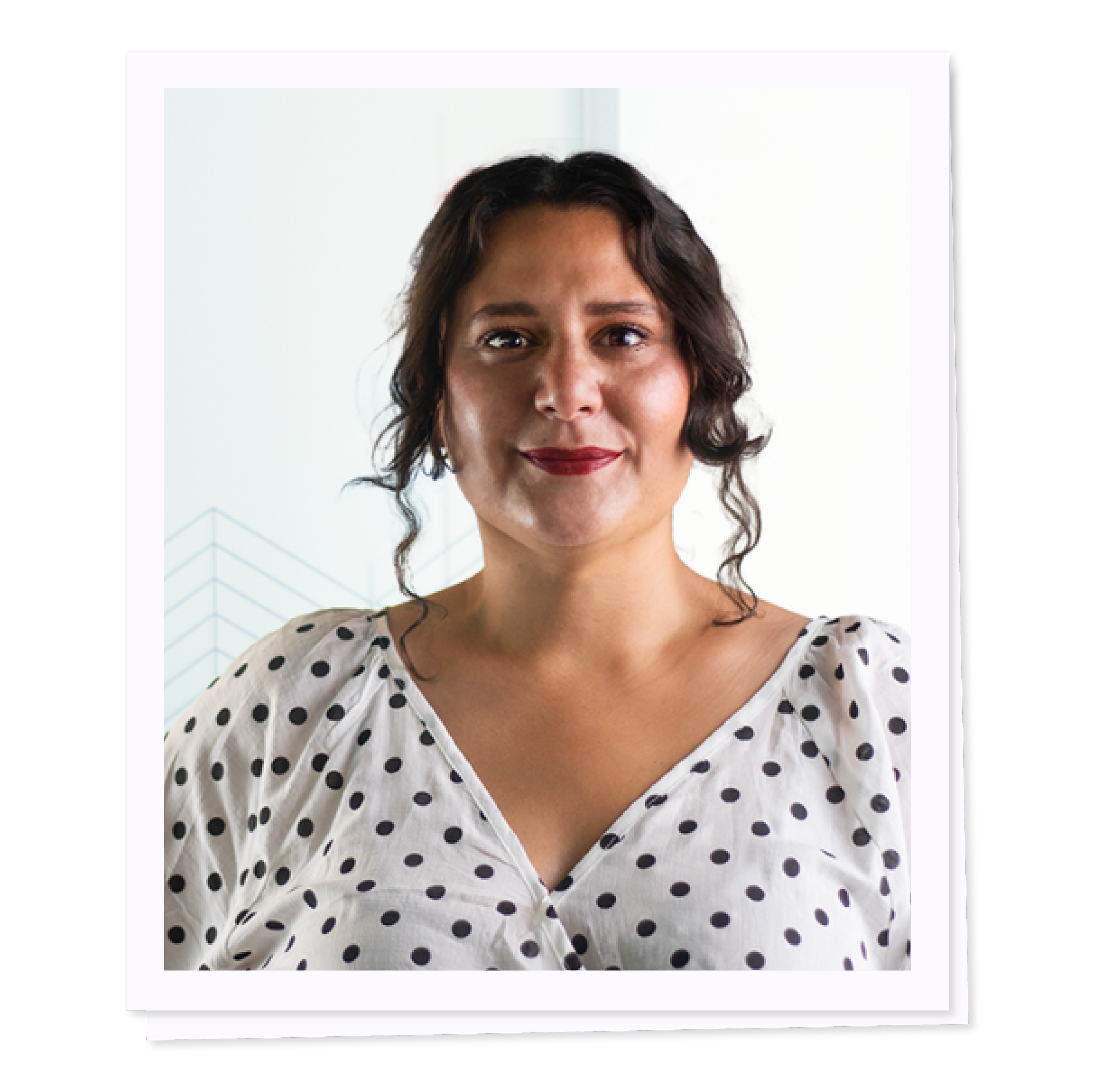 Person wearing a white polka dot blouse with curled hair.