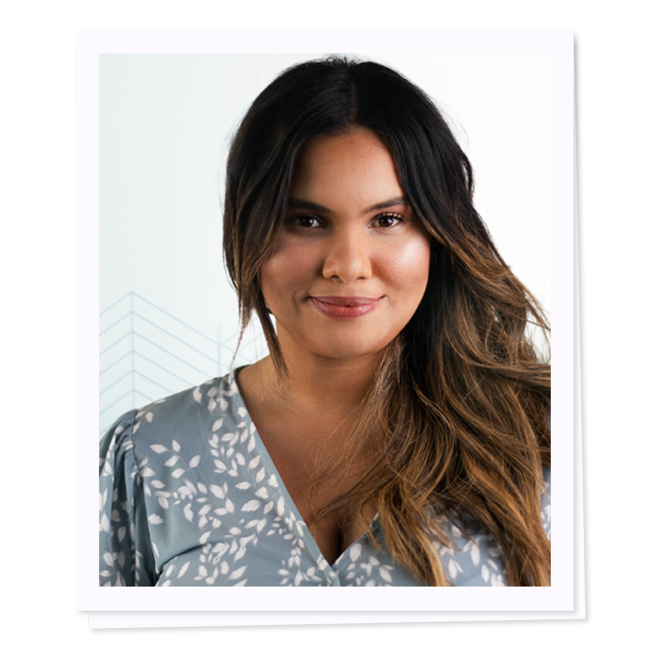 Woman with long hair wearing a blue patterned blouse, smiling at the camera.