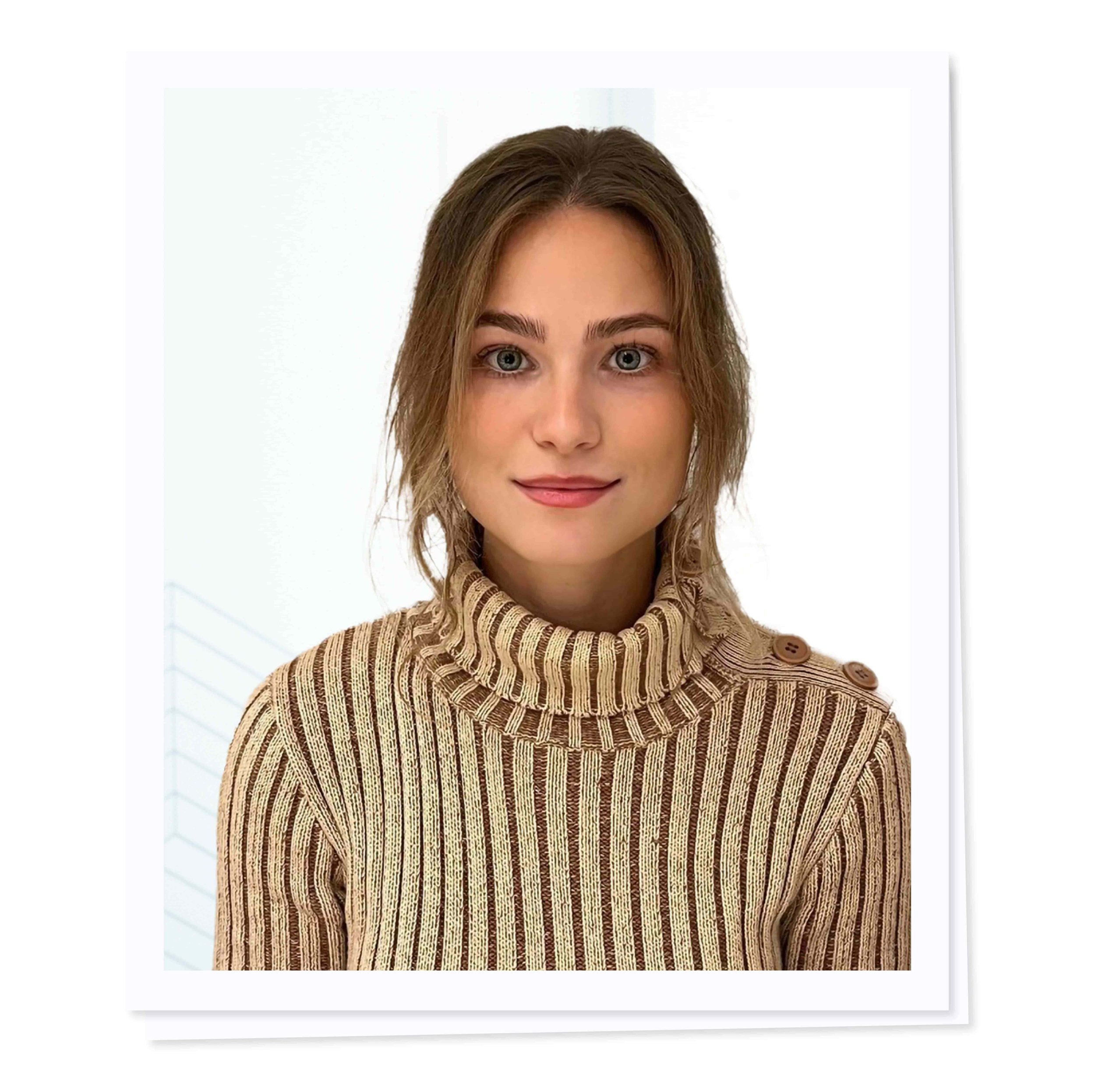 Person with brown hair wearing a striped turtleneck sweater, facing forward against a light background.