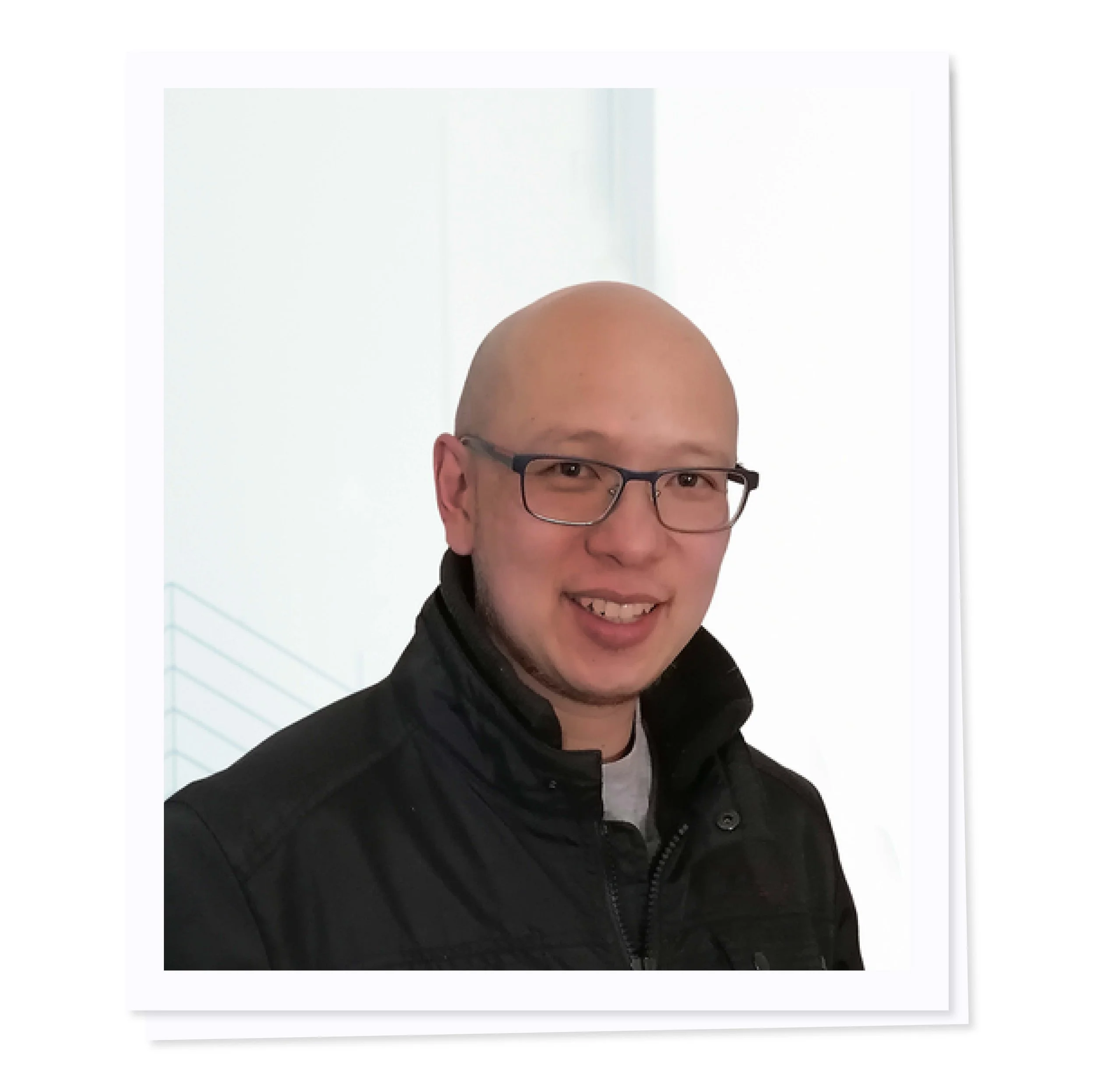 Person wearing glasses and a black jacket, smiling at the camera.