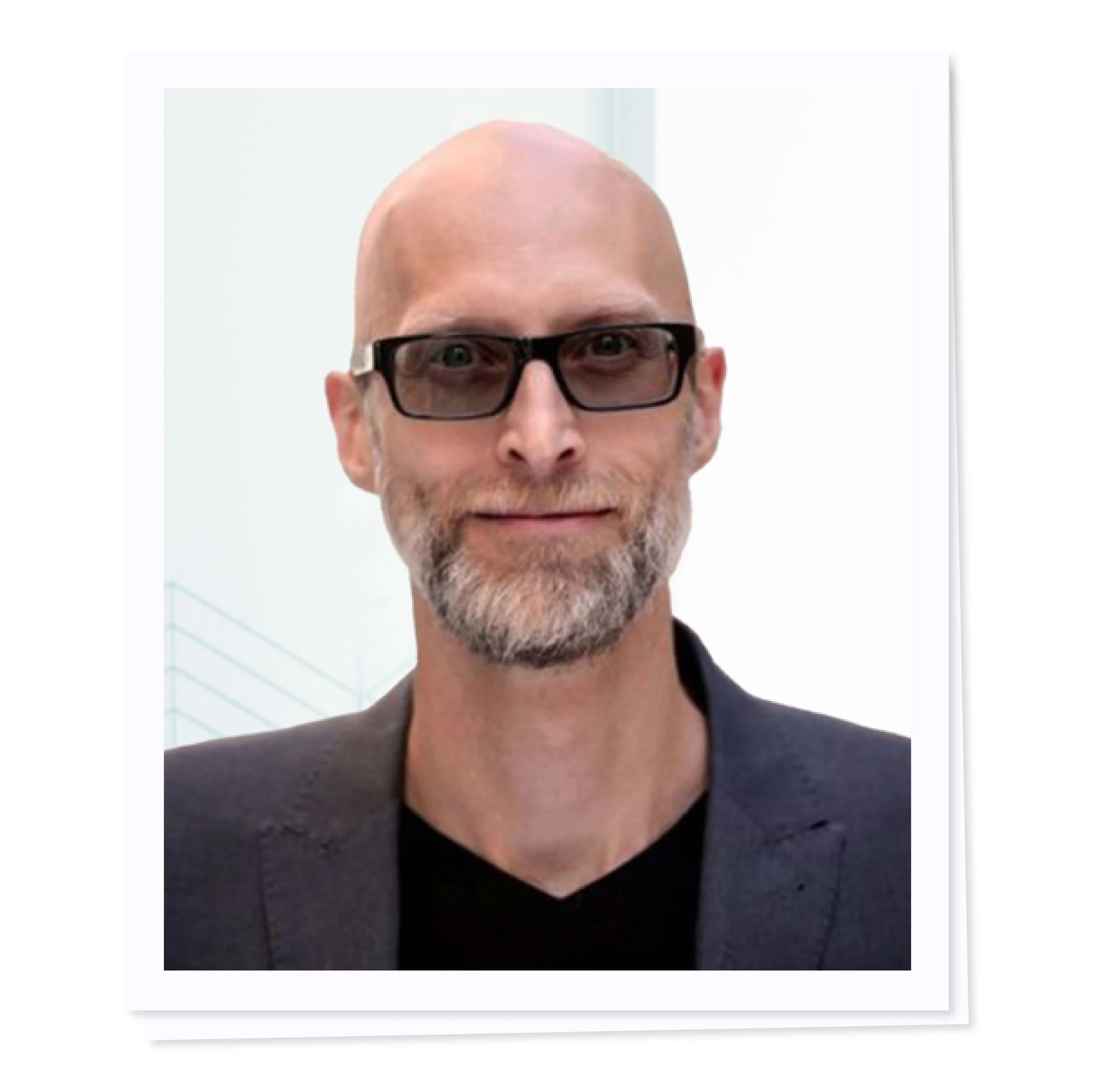 Bald man with glasses and beard in a suit.