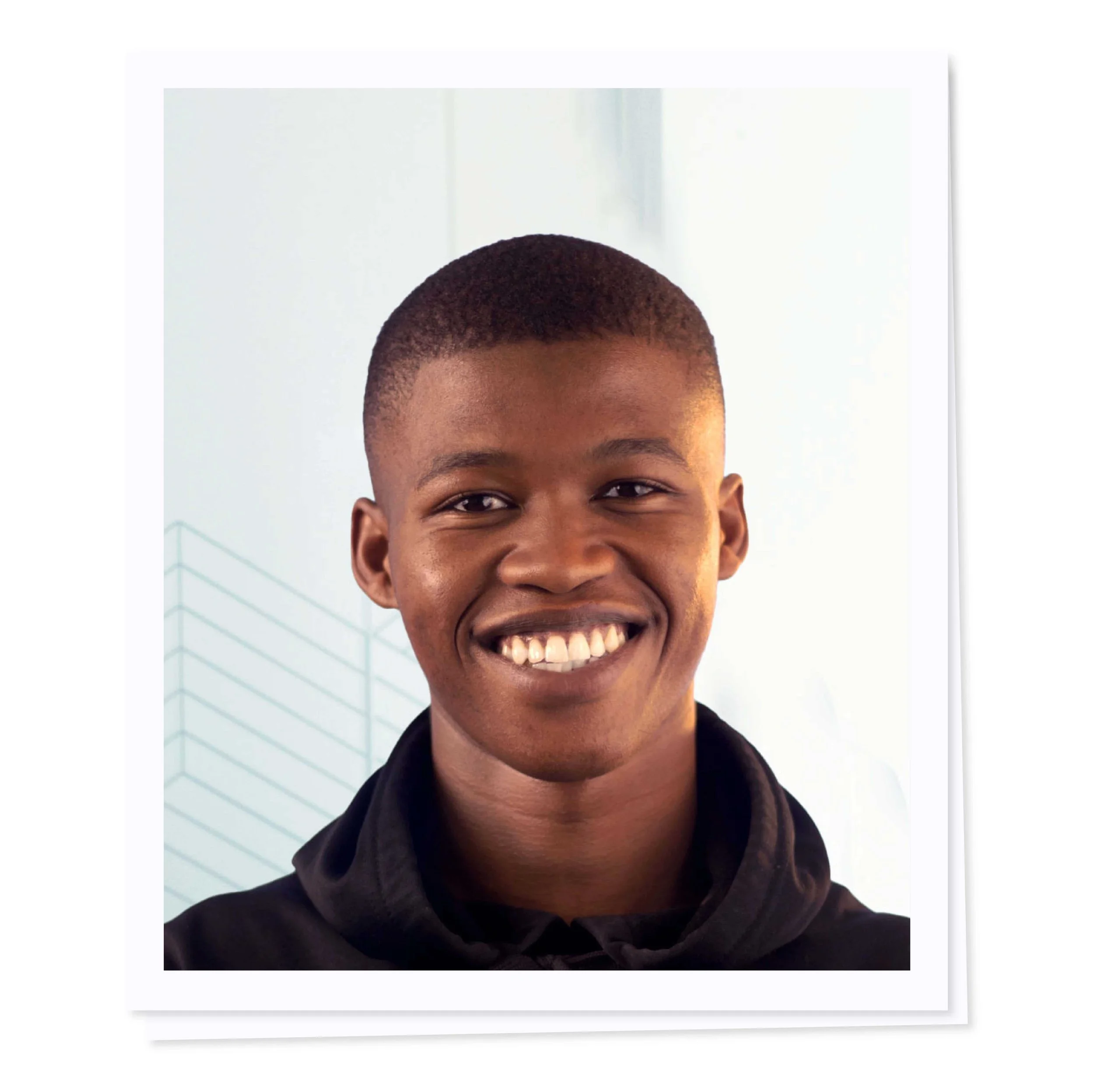 Smiling person in a dark hoodie against a light background.