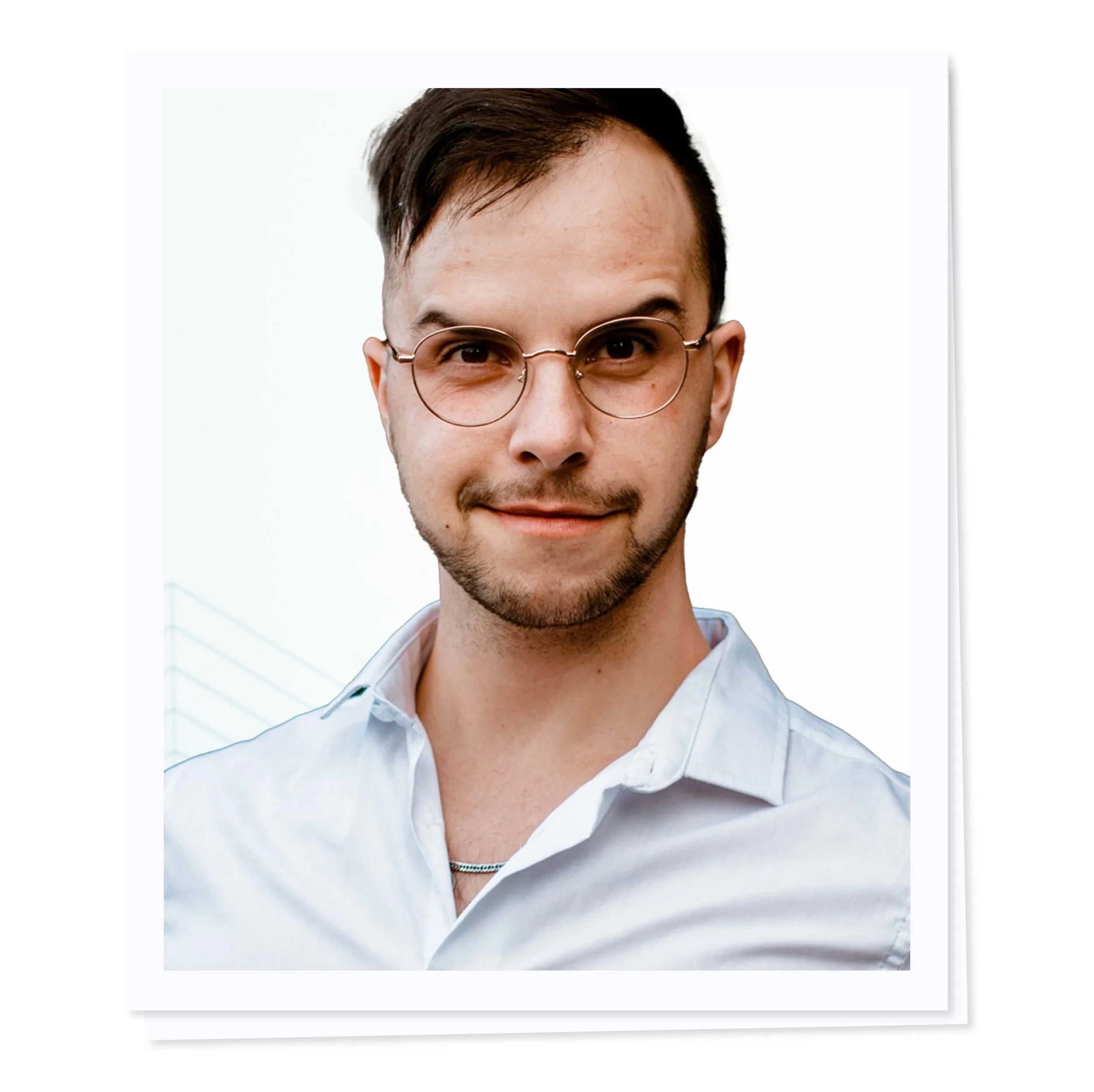 Man with glasses and short hair wearing a white shirt against a plain background.