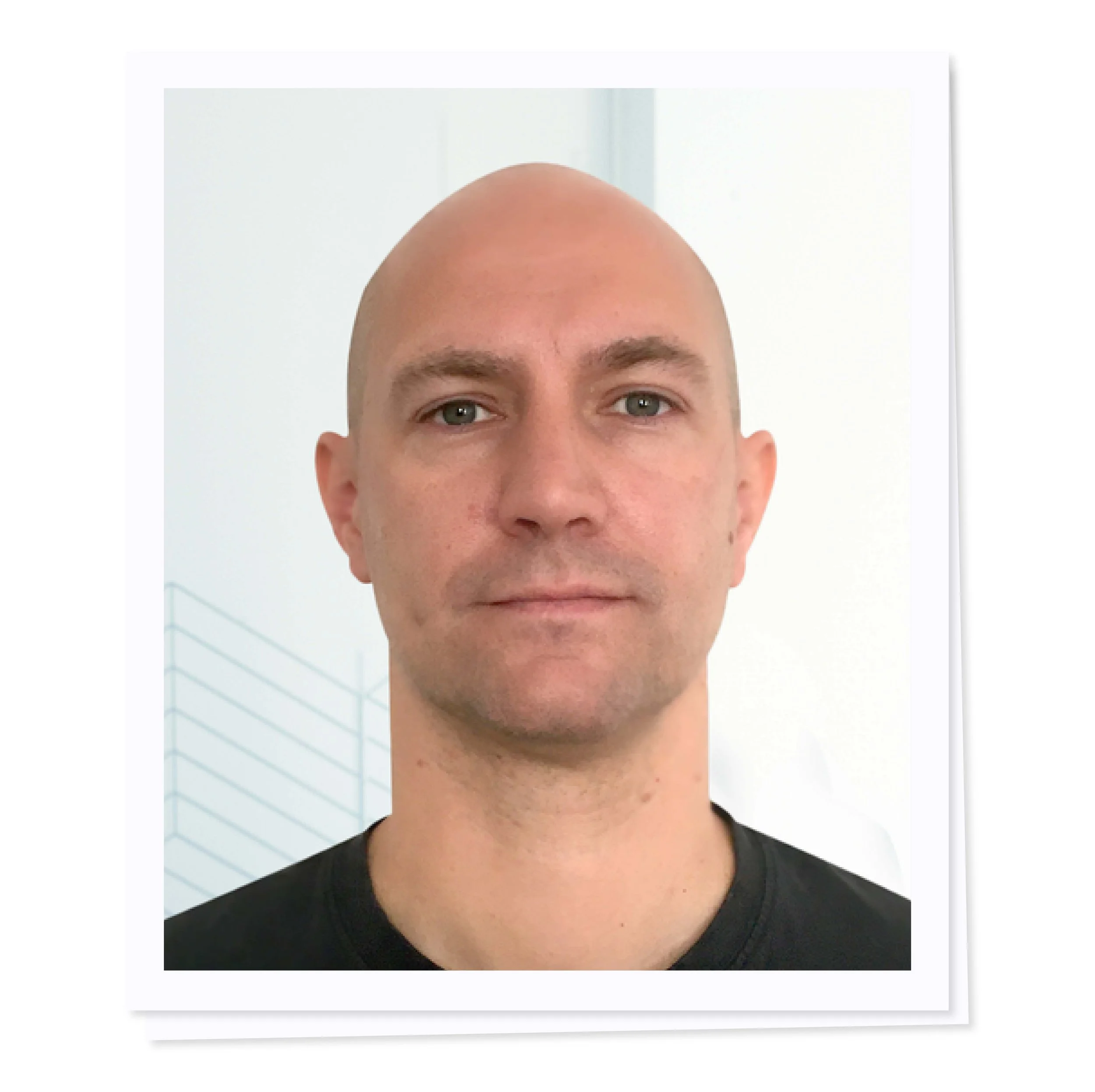 Bald man in a black shirt looking at the camera