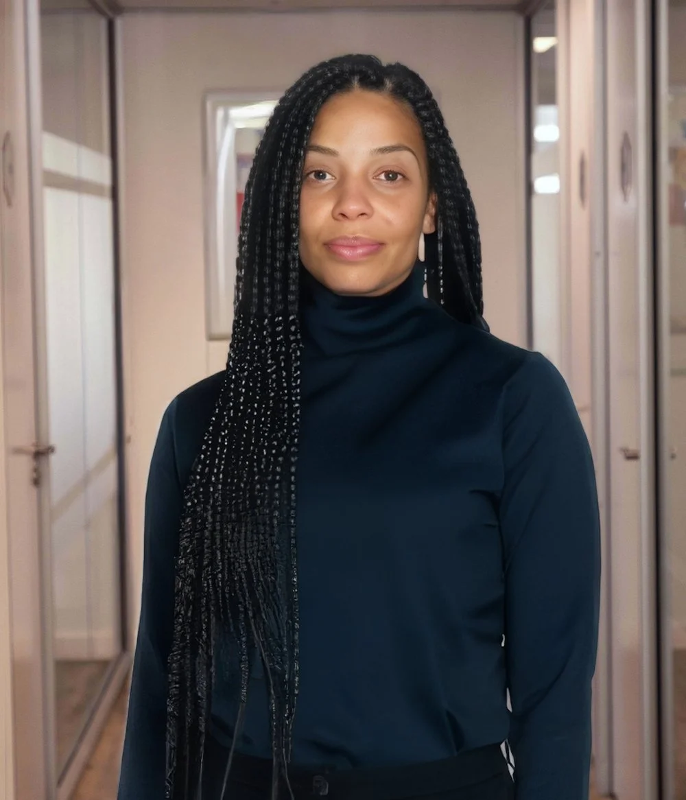 Person with short blonde hair wearing a white tank top against a light background.