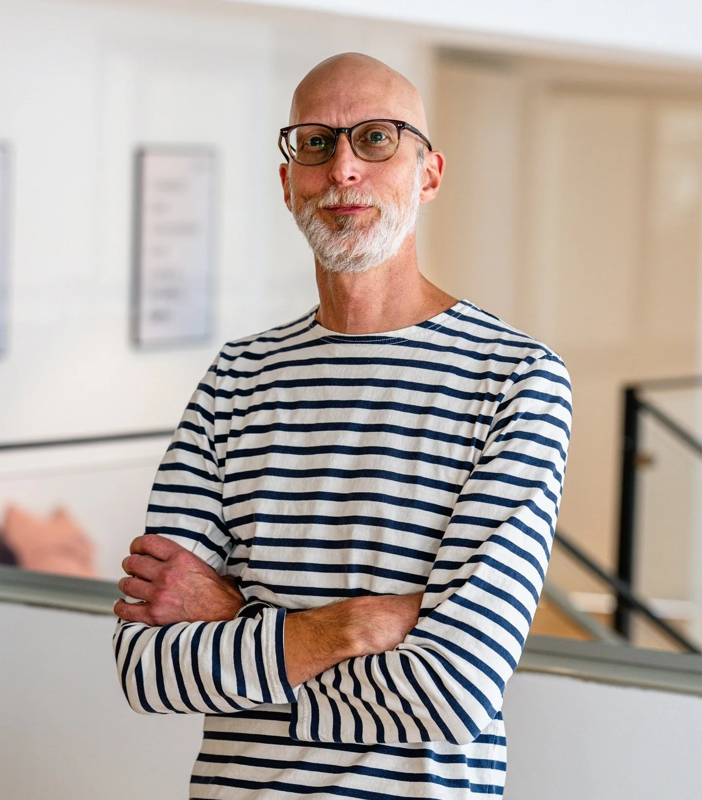 Bald man with glasses wearing a suit.