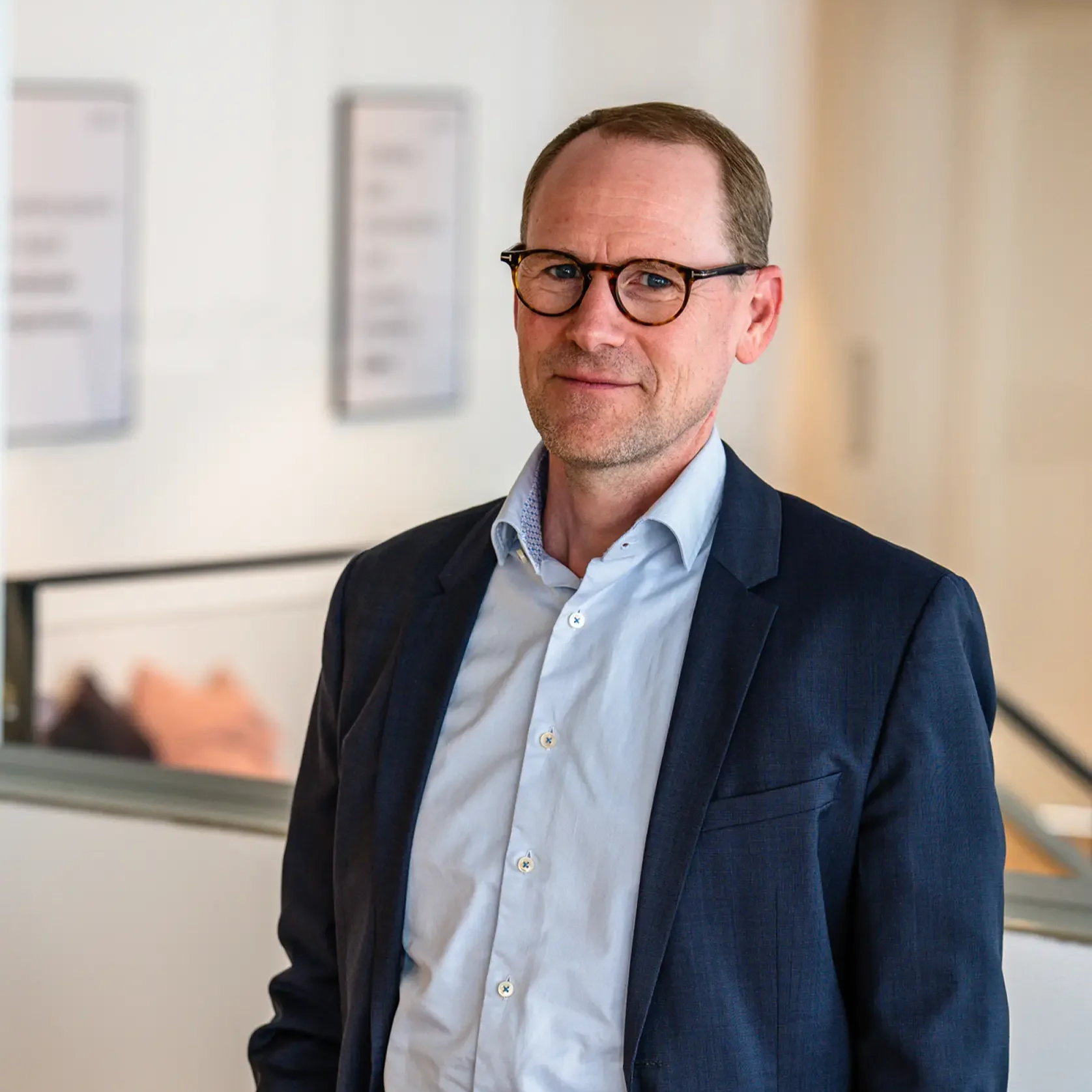 Man wearing glasses, black sweater, and blue shirt