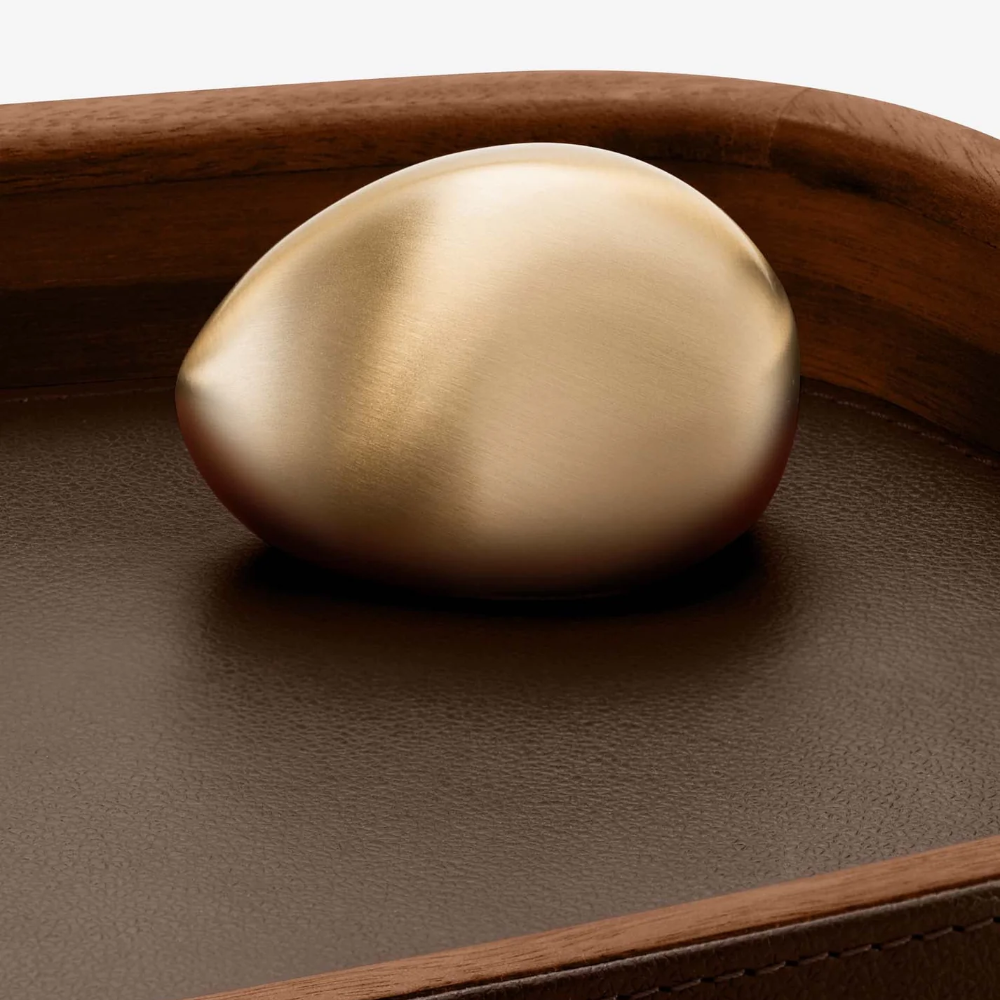 LibraryCollection_PebbleAccessoryTray_BrownLeatherWalnutWoodBrass_PebbleDetail_Assouline_2025-1000x1000.png