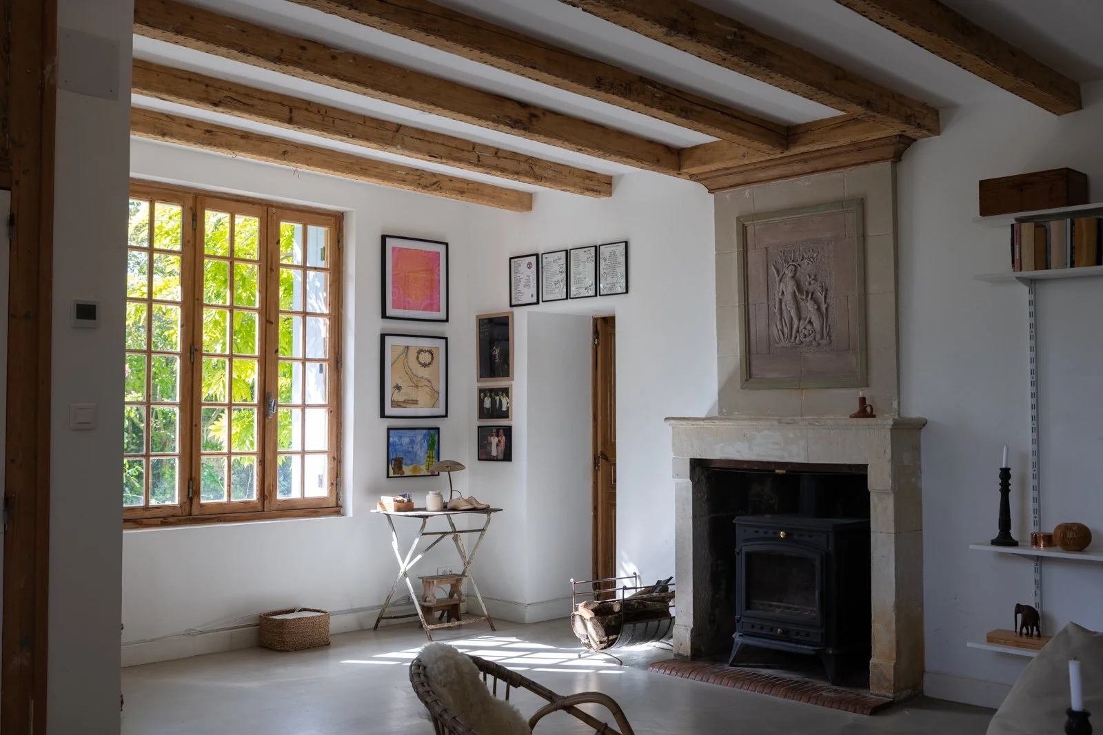 Living room with a large window, a stone fireplace, wall art, and a cozy armchair.