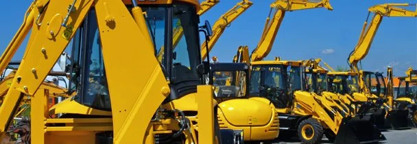 Row of yellow construction backhoe loaders parked outdoors under a clear blue sky.