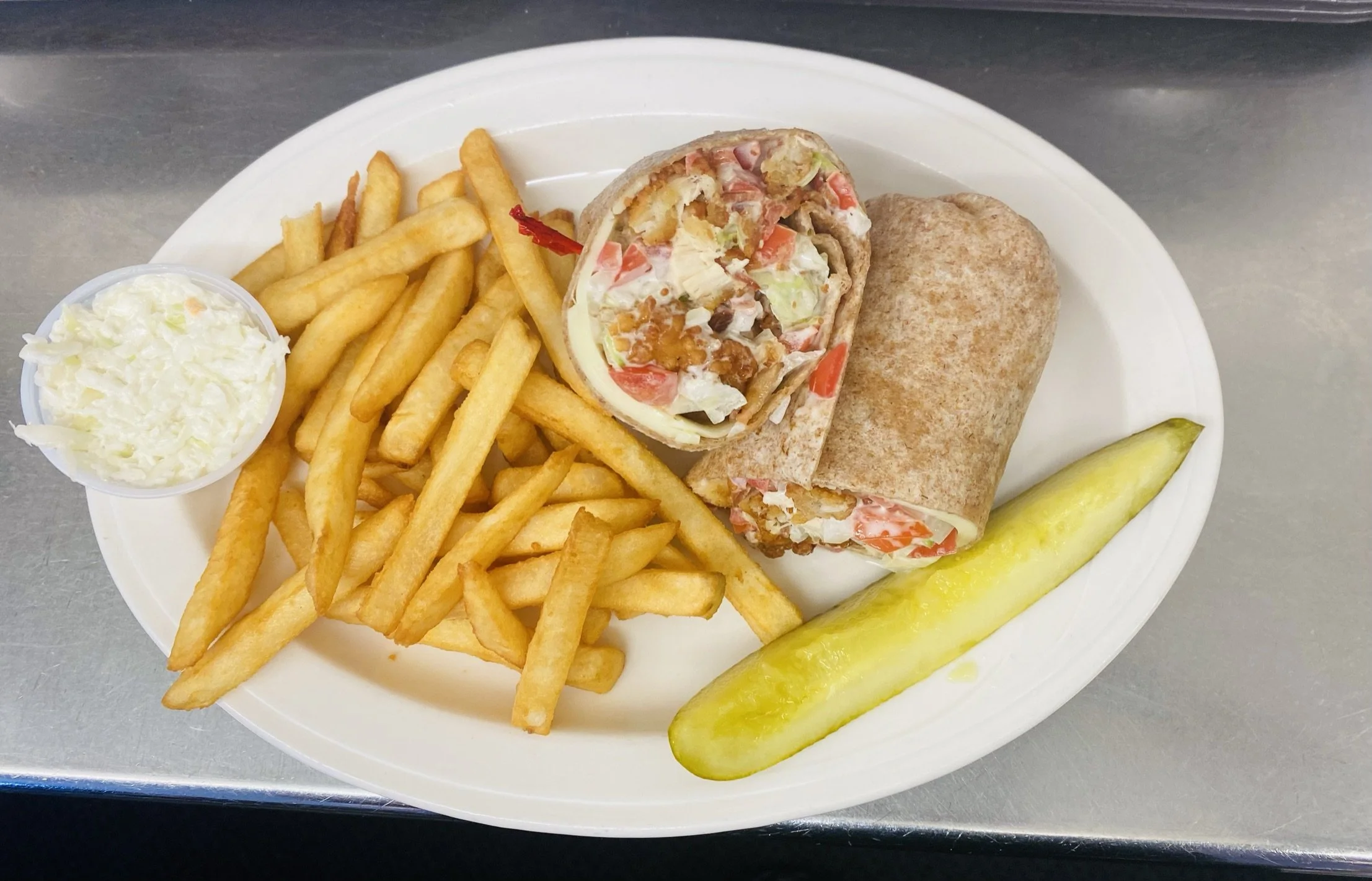 Plate with fries, coleslaw, a breakfast burrito, a breakfast wrap, and a pickle spear.