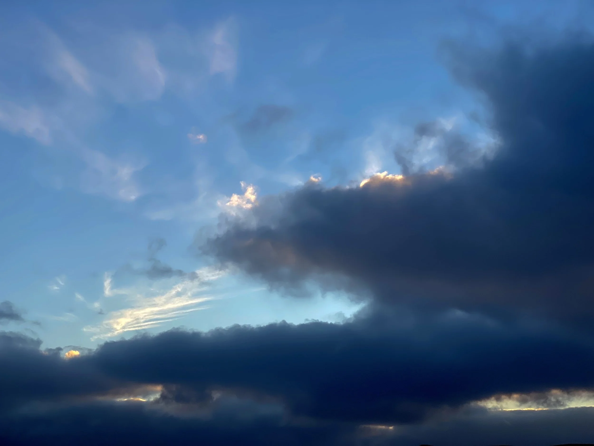 cloudy sky during sunset with patches of blue sky and various dark and light clouds