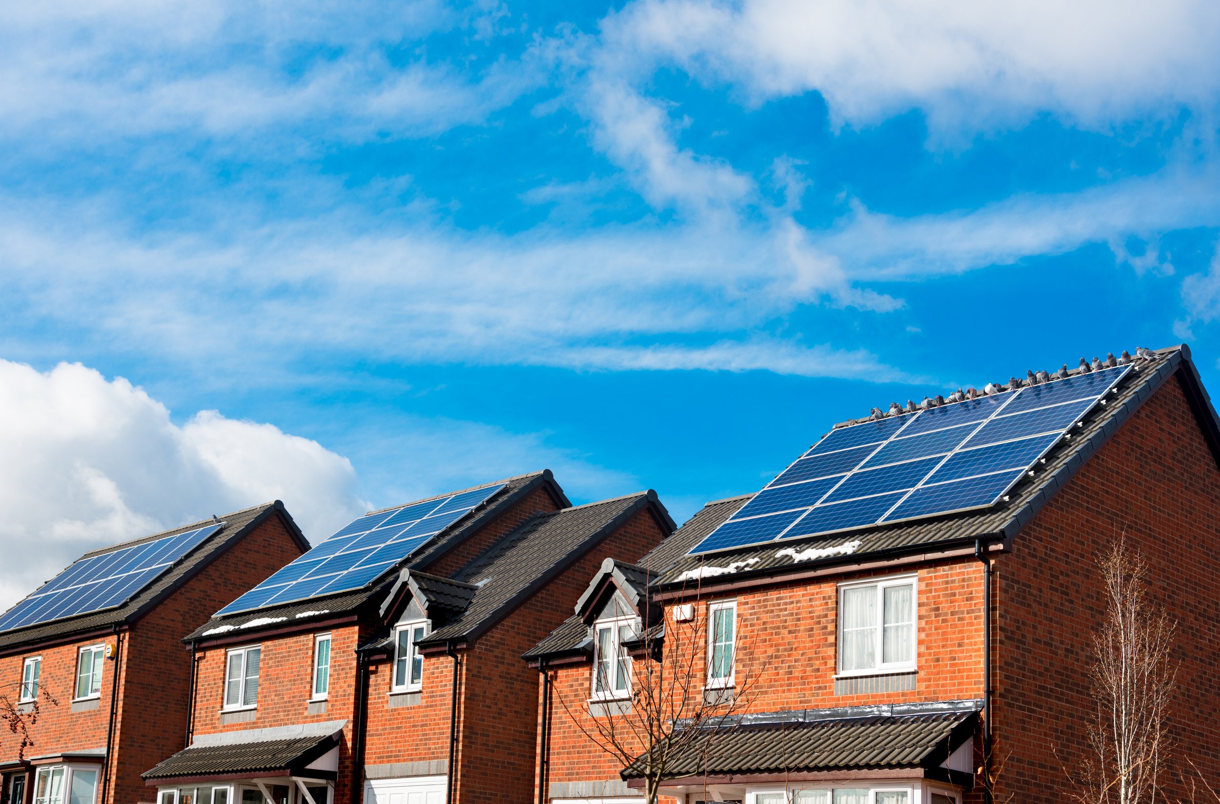 Row of brick houses with solar panels under blue sky