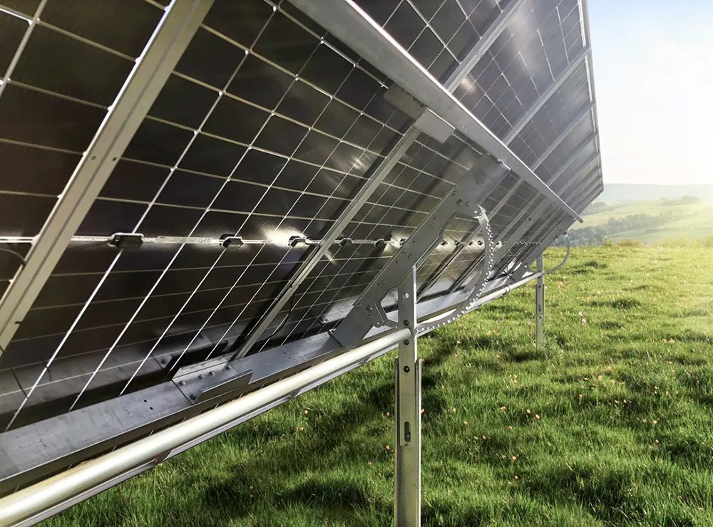 Close-up of solar panels installed outdoors on a grassy field with a view of distant hills.