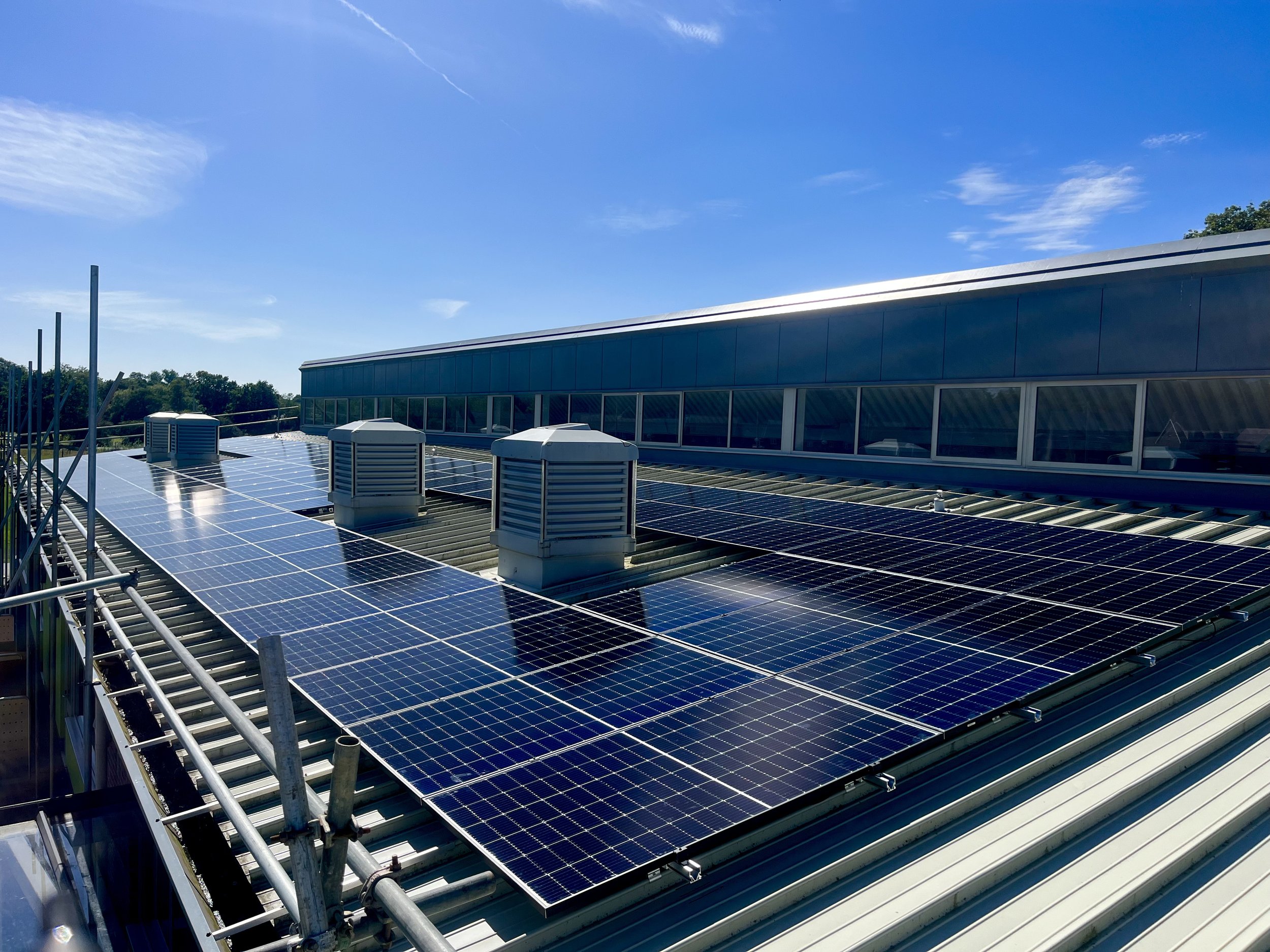 Solar panels installed on the roof of a building under a clear blue sky.