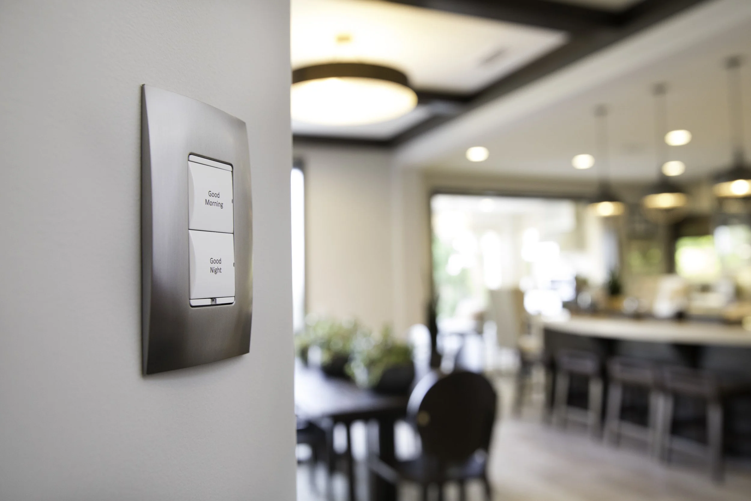 Light switch with 'Good Morning' and 'Good Night' buttons on a wall in a bright and modern indoor setting.
