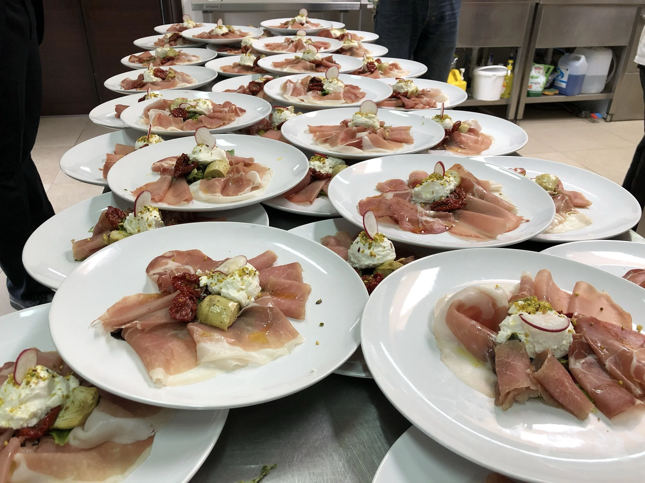 Plates of prosciutto antipasti lined up and ready to serve
