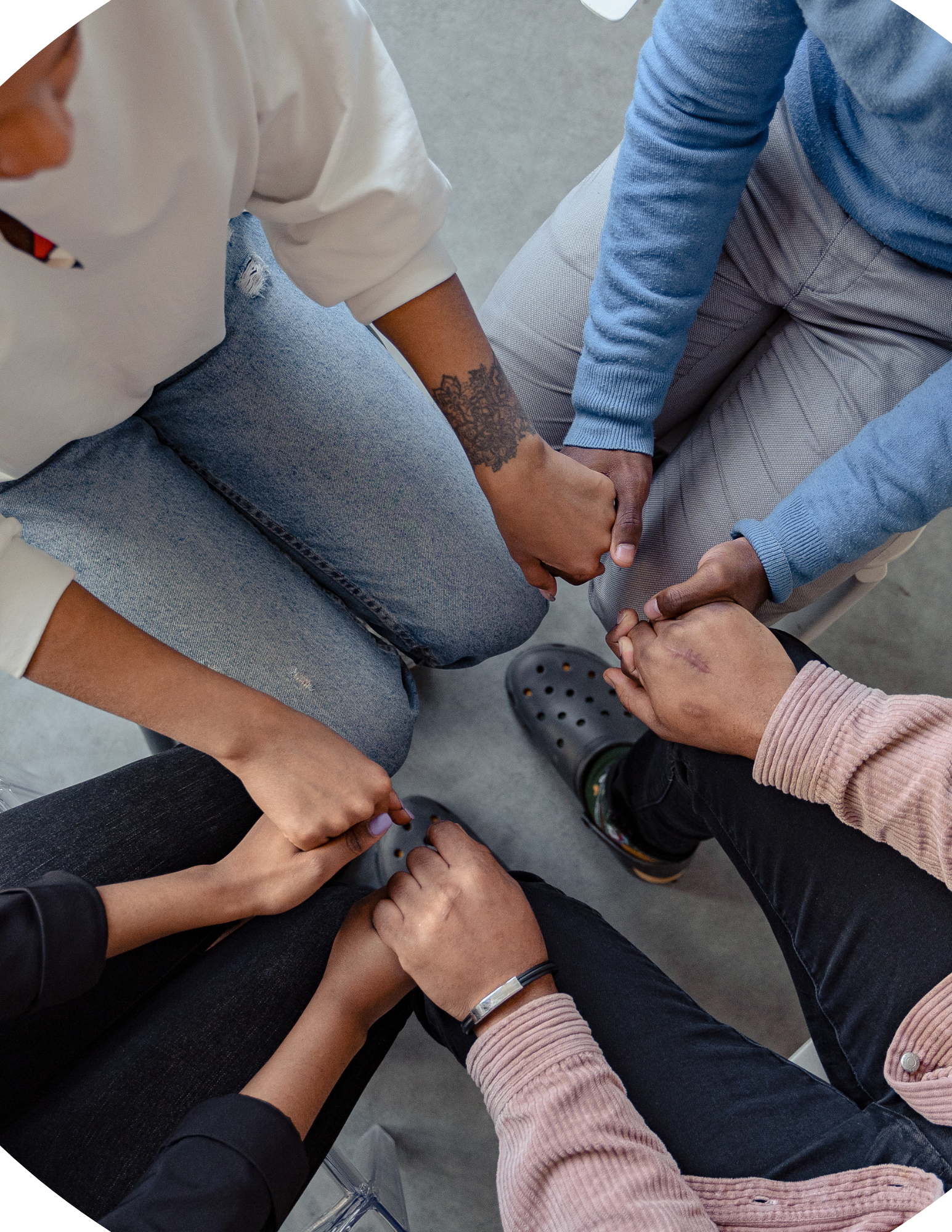 Five people holding hands together in a circle, showing unity and support.