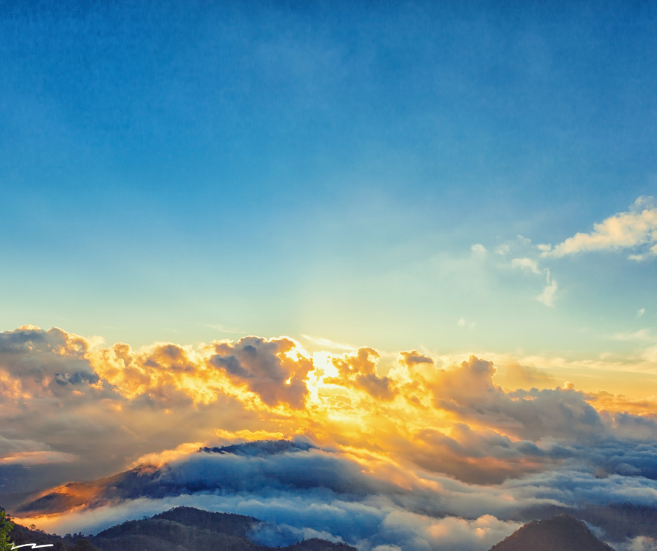 Sunset over a mountain range with clouds and colorful sky.