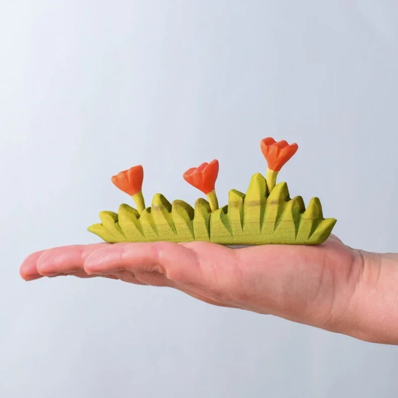 grass with orange flowers large bumbu toys treleker i hånd.webp