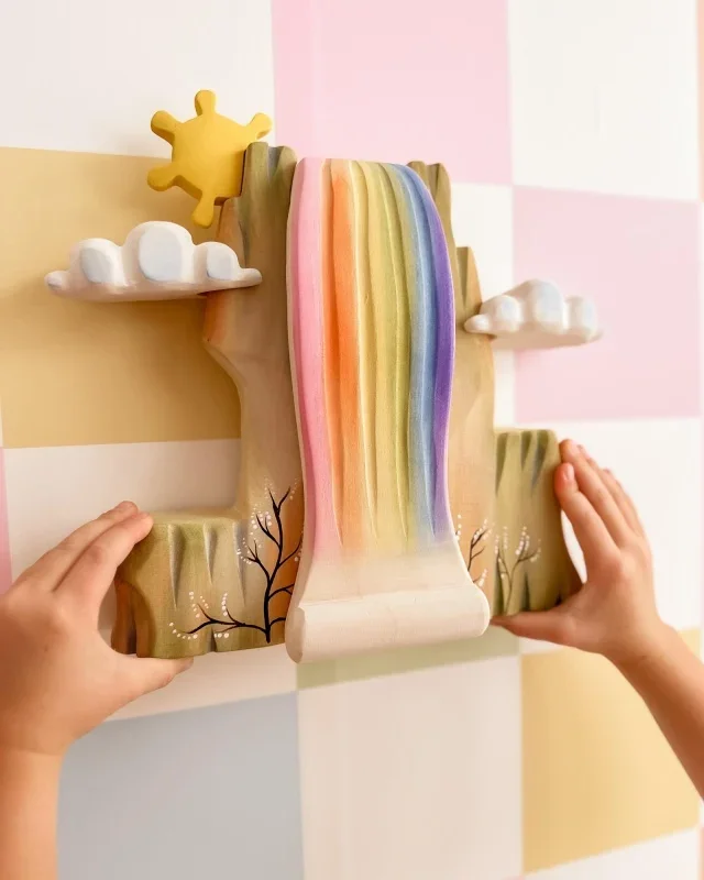 rainbow-cliff~ regnbue klippe bumbu treleker med barnehender.webp