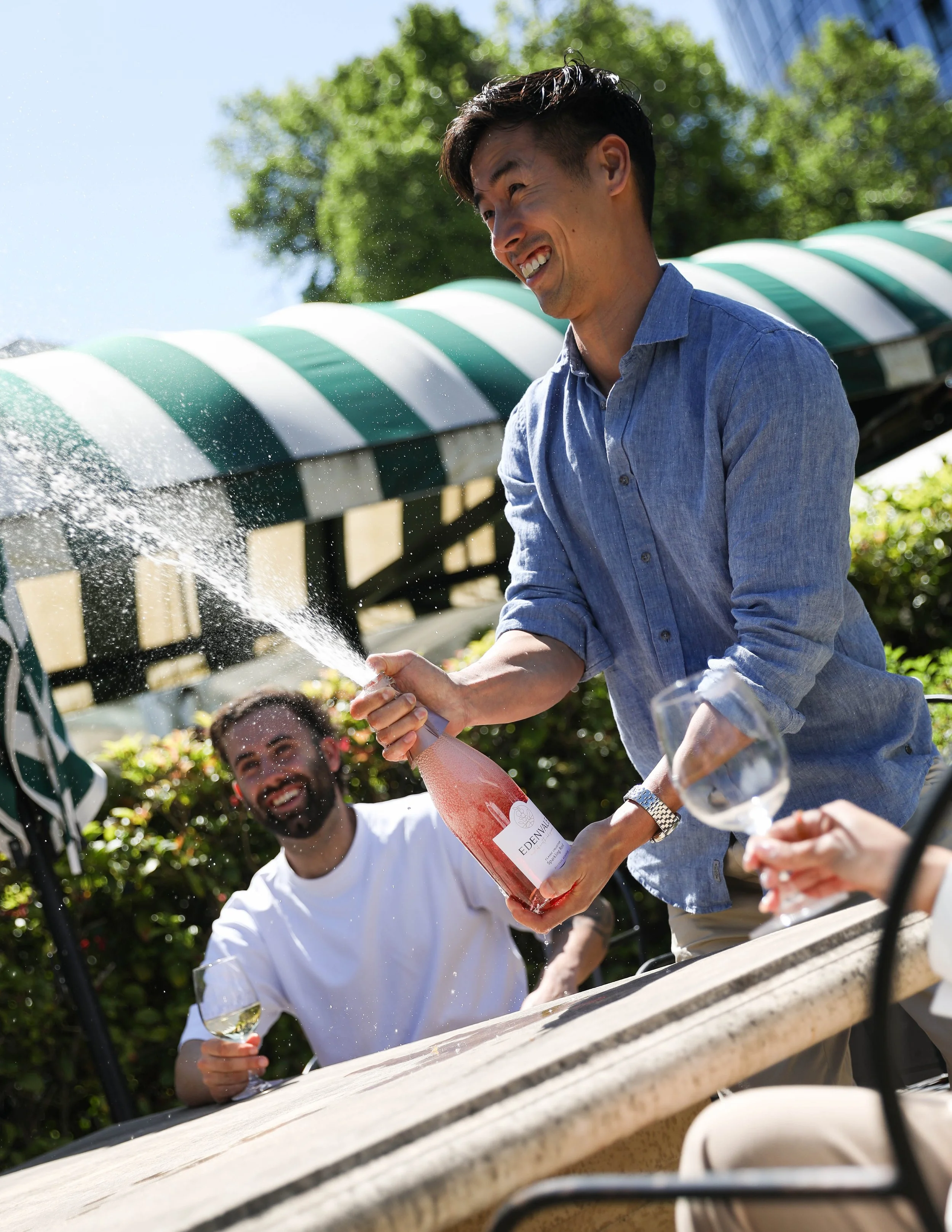 Ray Yee opening a bottle of rosé outdoors with friends, Edenvale Wines