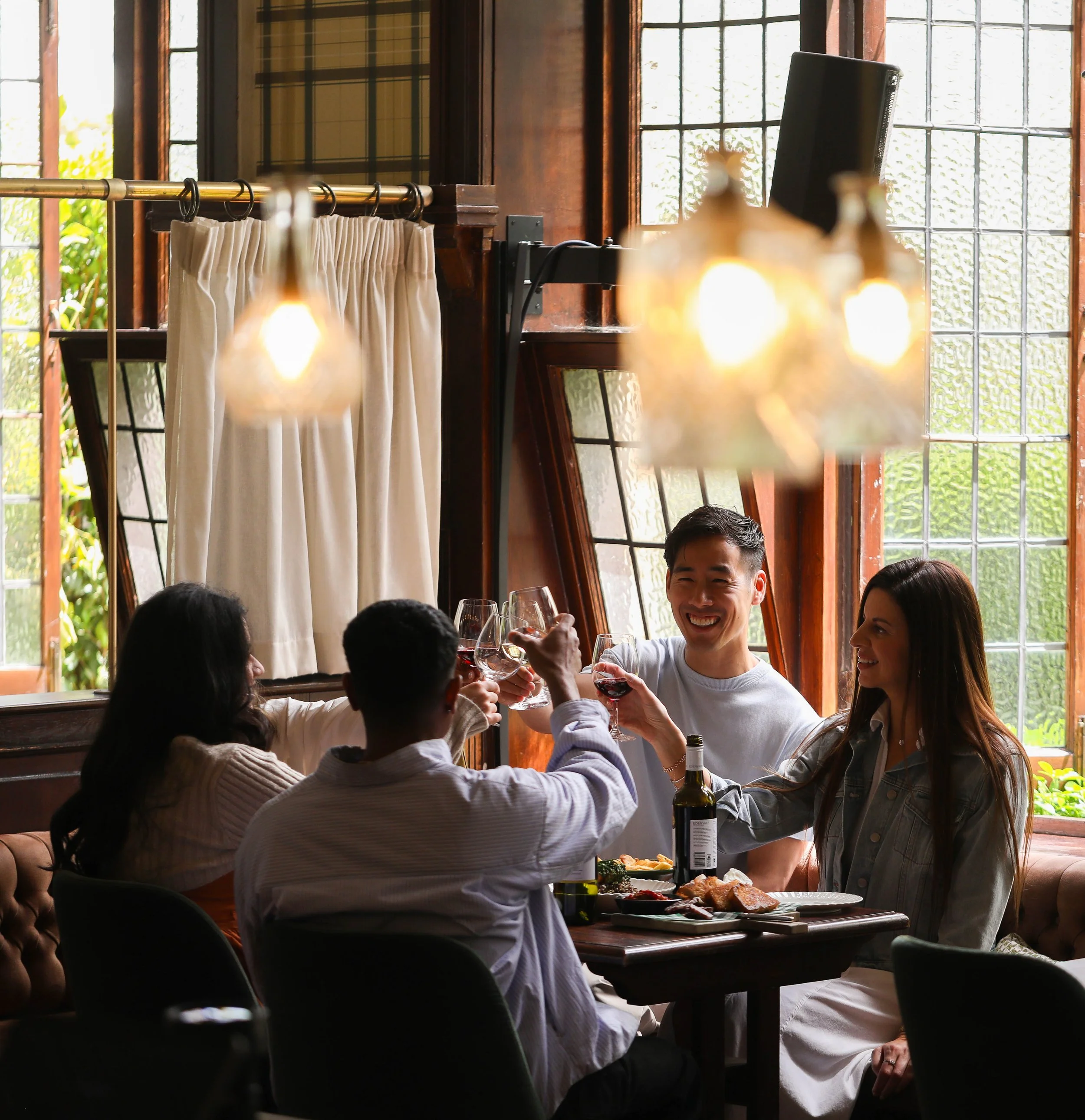 Ray Yee with friends raising wine glasses at a restaurant table, Edenvale Wines