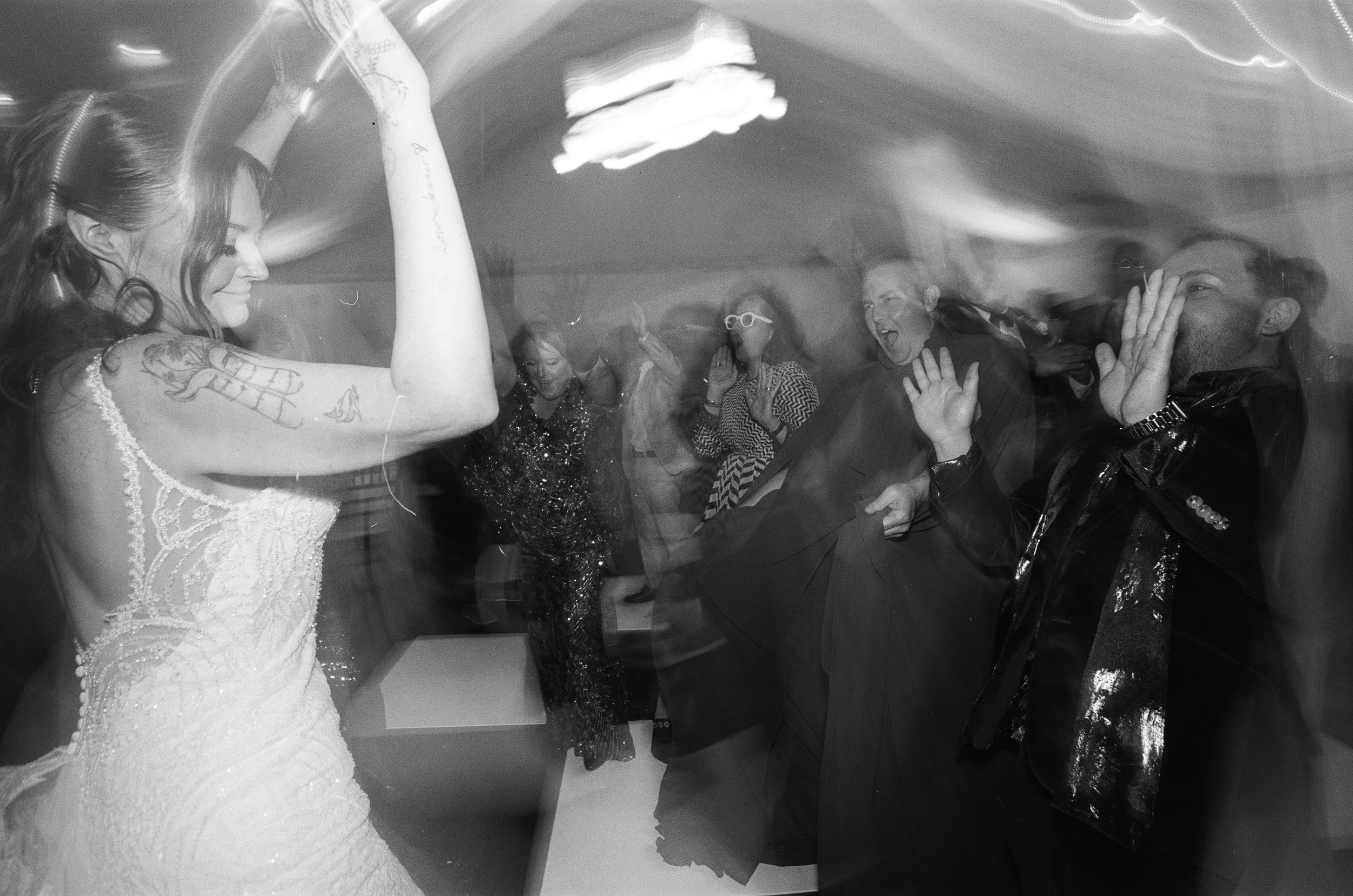 People dancing and enjoying at a party or celebration, with a woman in a glittery dress and others around her.