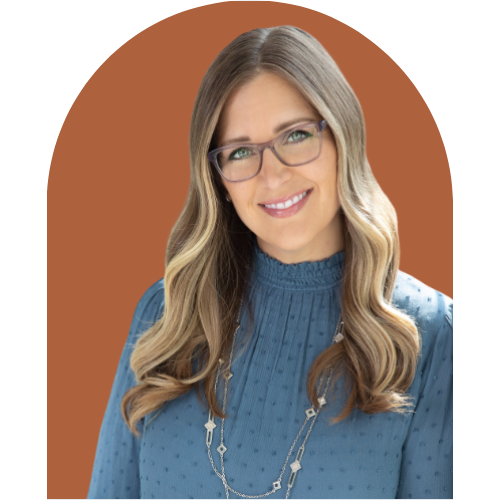 A woman with long wavy blonde hair, wearing glasses and a blue blouse, smiling in front of a brown and black background.