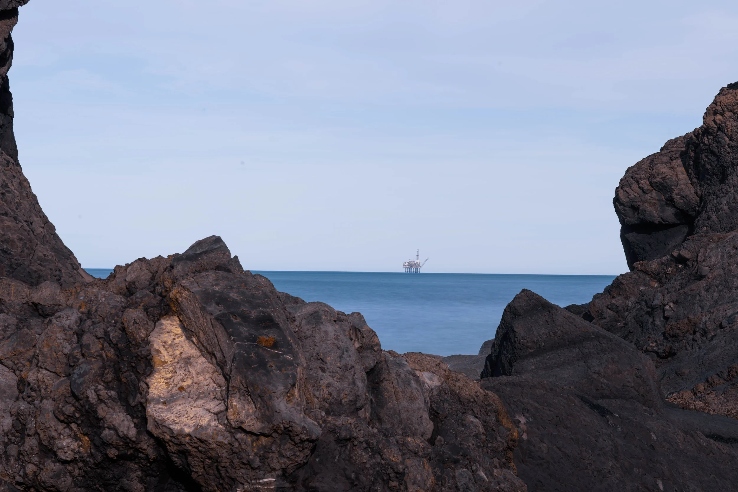 An odd combination of oil rig and coastal rocks.