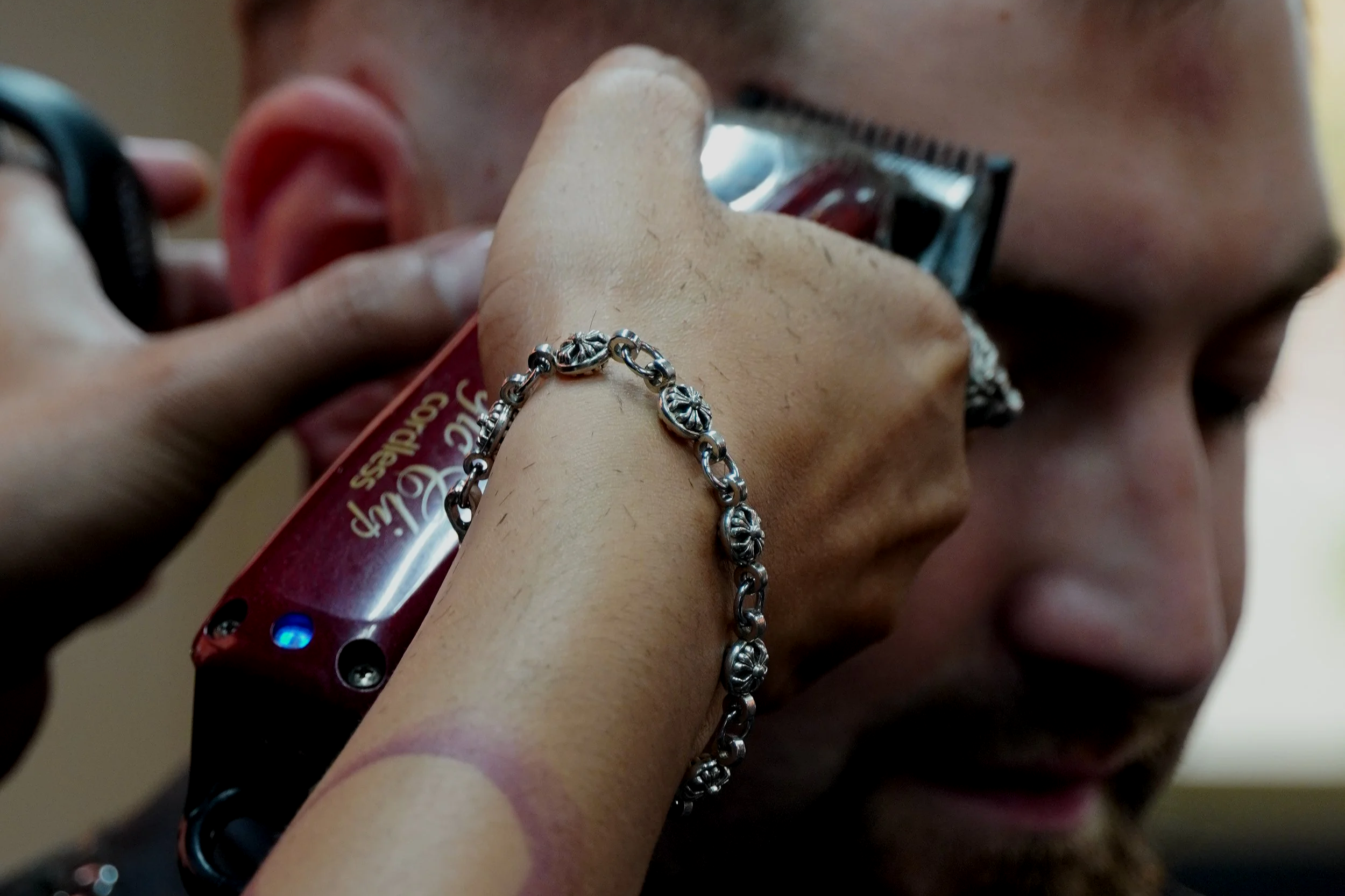 Person getting a close shave with an electric razor, wearing a bracelet with floral design.