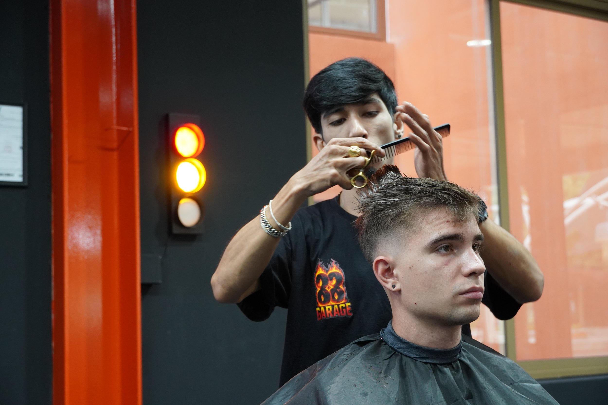 Barber giving a haircut to a young man in a barbershop.
