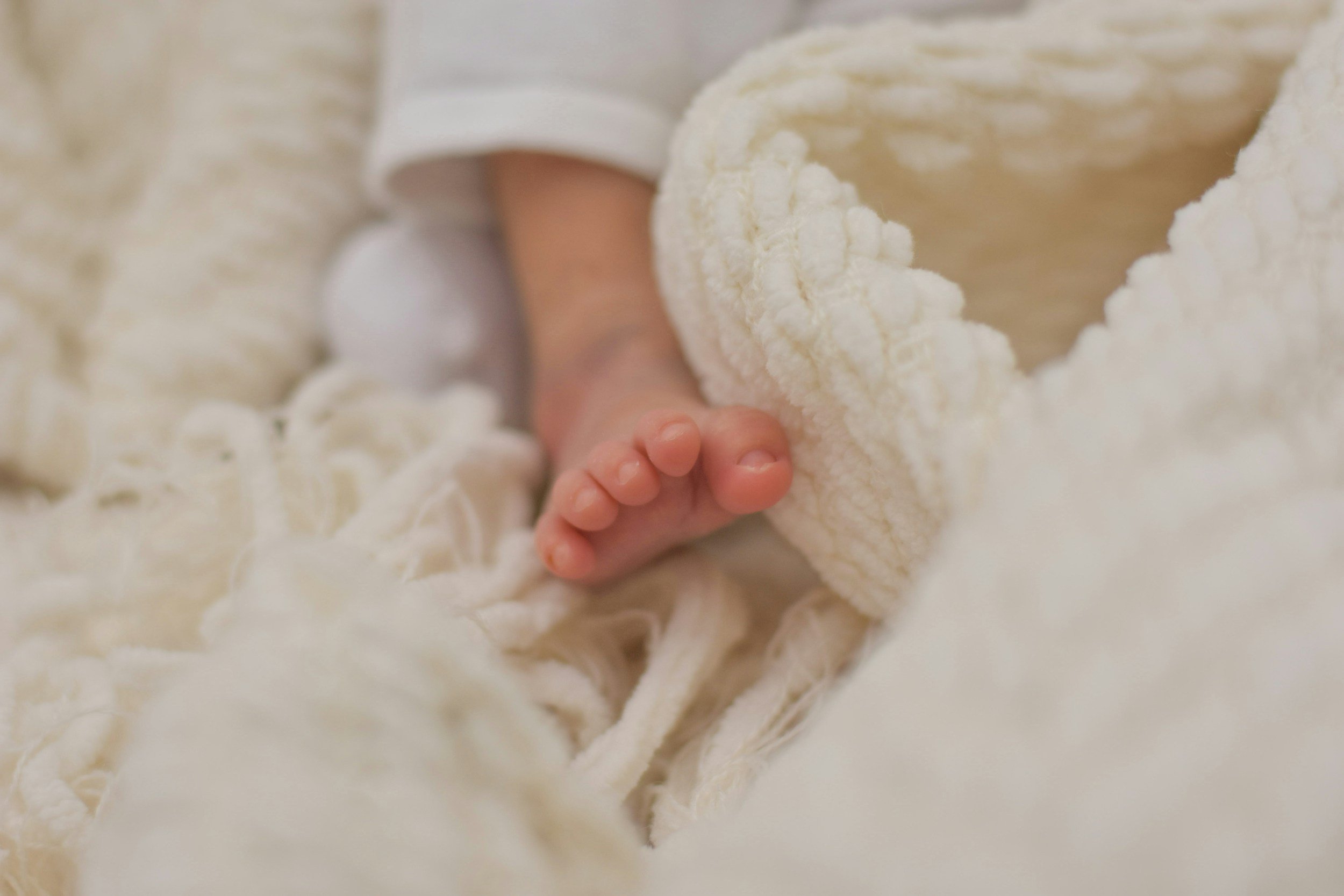 Close-up of a baby hand holding a piece of cheese surrounded by shredded cheese.