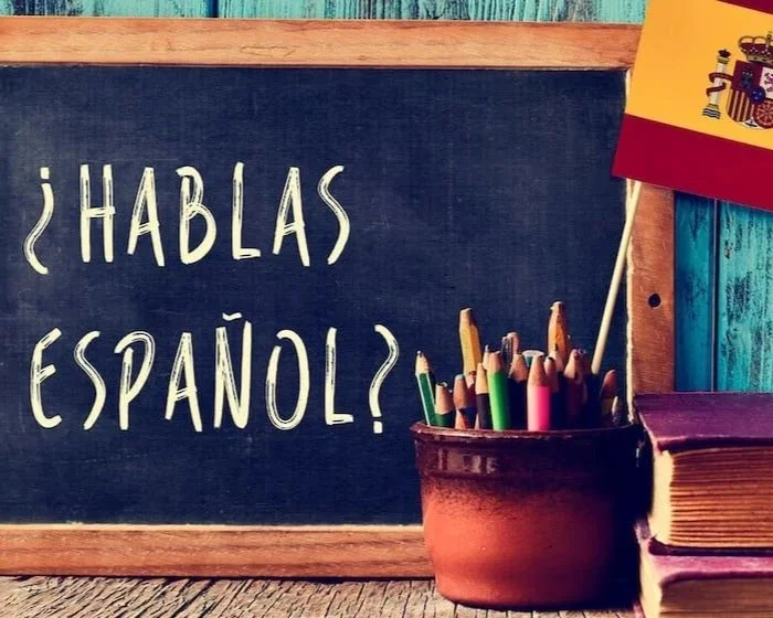 Chalkboard with the question '¿Hablas español?' written on it, a pot of colored pencils, and a Spanish flag.