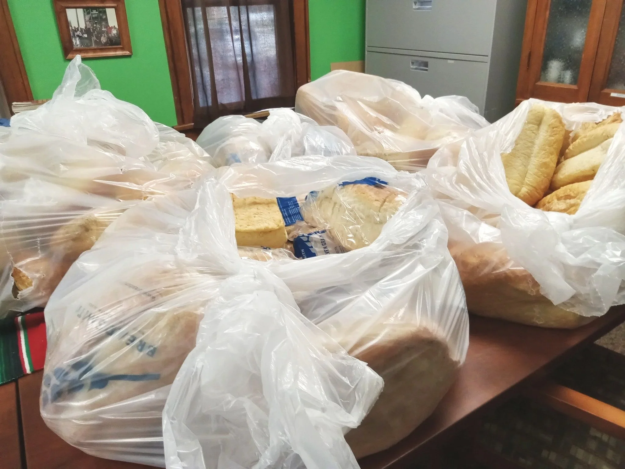 Several large plastic bags filled with sliced bread on a kitchen table.
