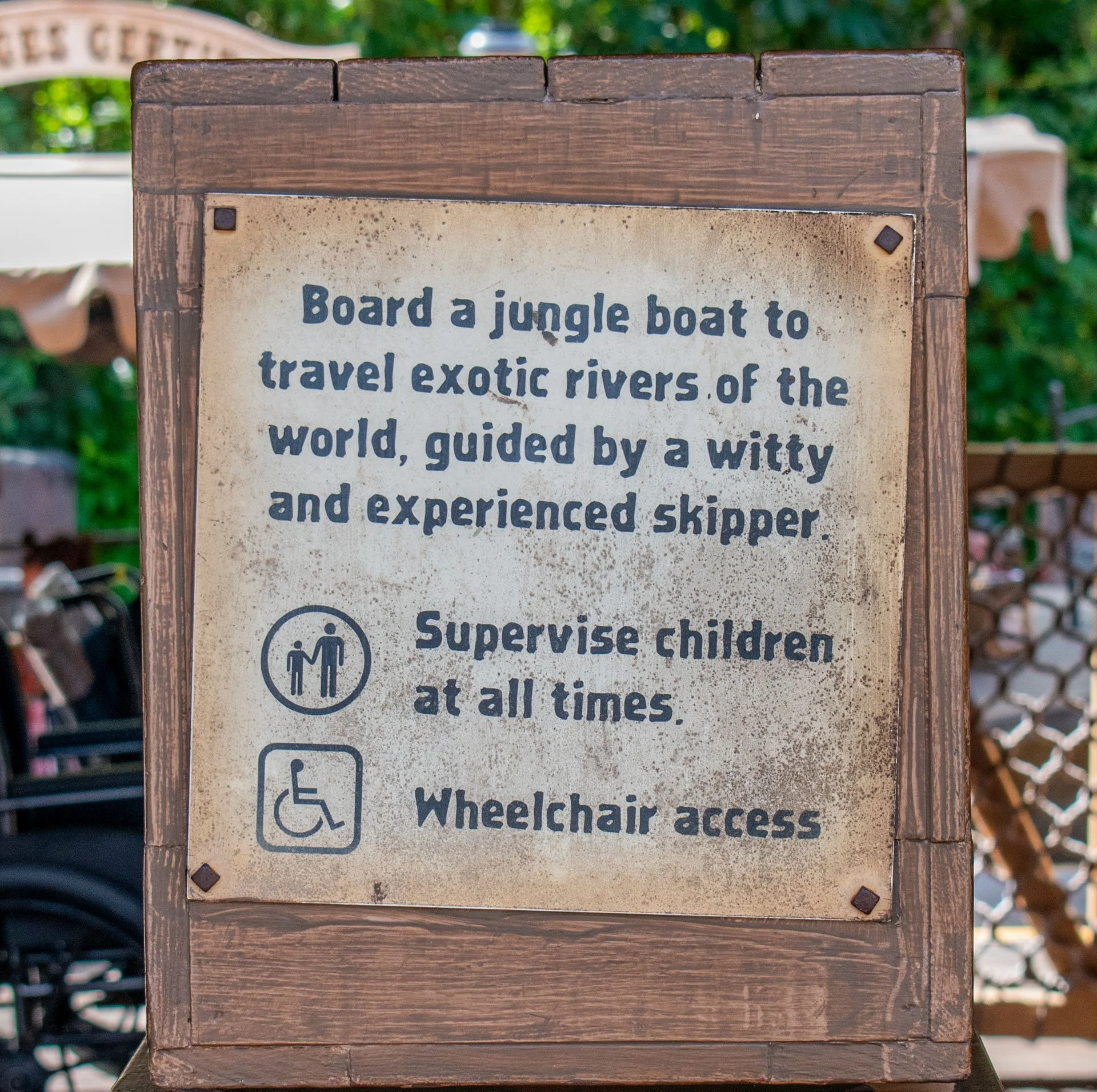 A sign instructs visitors to board a jungle boat to travel exotic rivers guided by a skipper. It also mentions supervising children and wheelchair access.