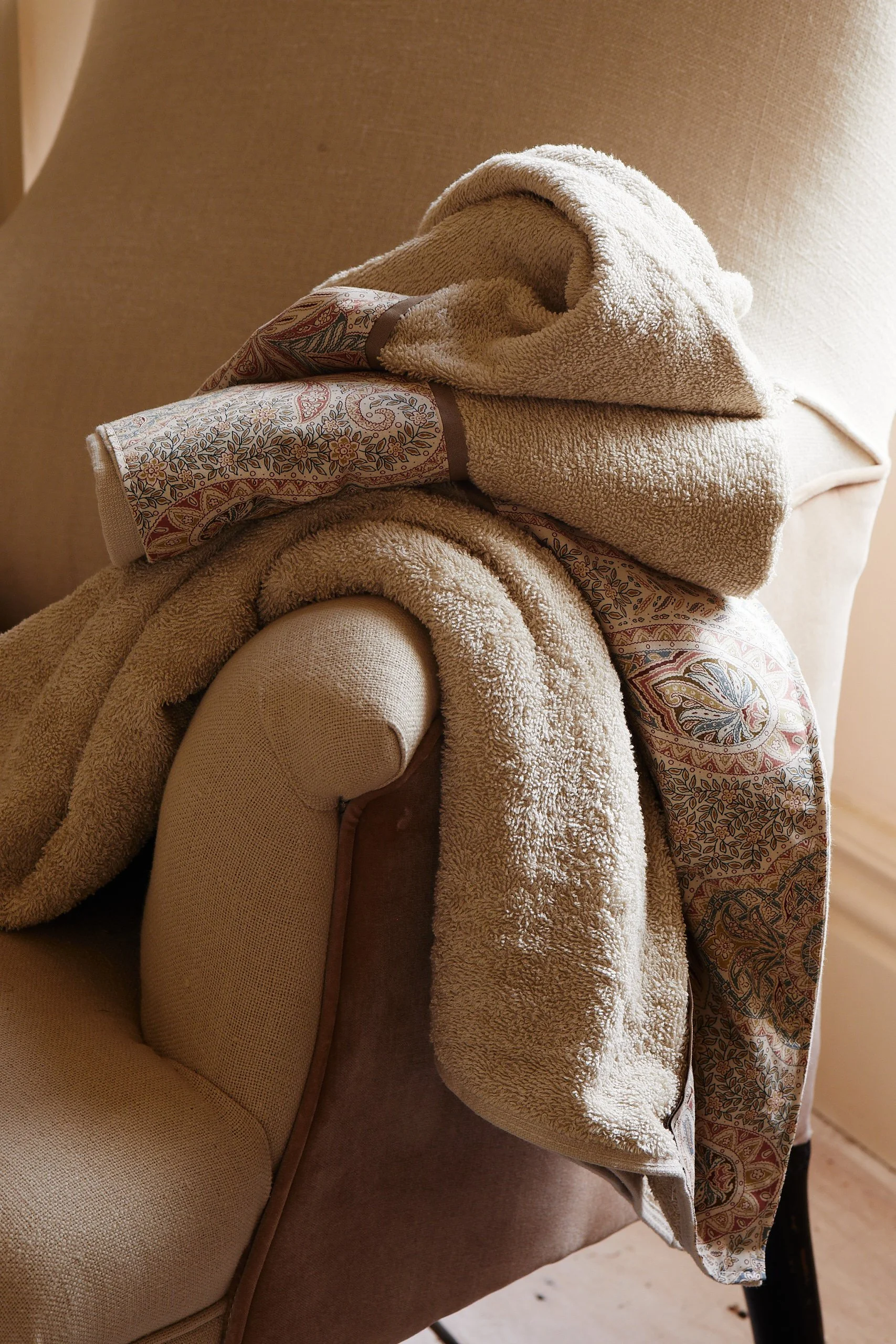 Draped beige towel and patterned fabric on a beige upholstered chair.