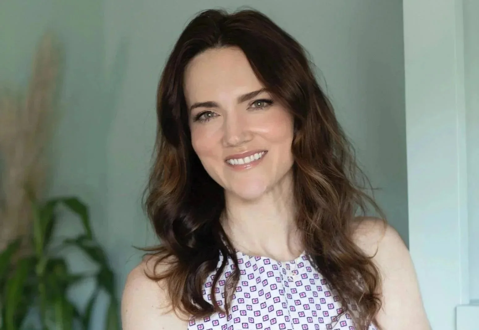 Therapist in Atlanta with brown hair and checkered shirt leans against wall and smiles.