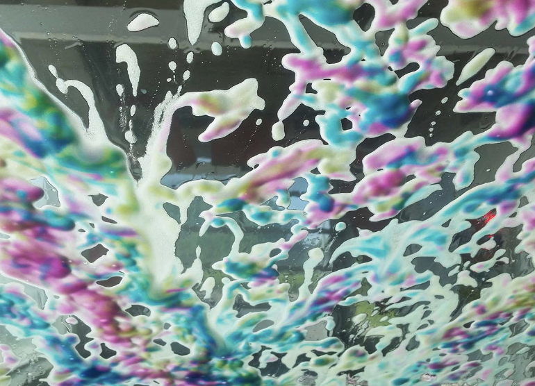 Colorful soap bubbles and foam mixture with pink, blue, green, and white colors.