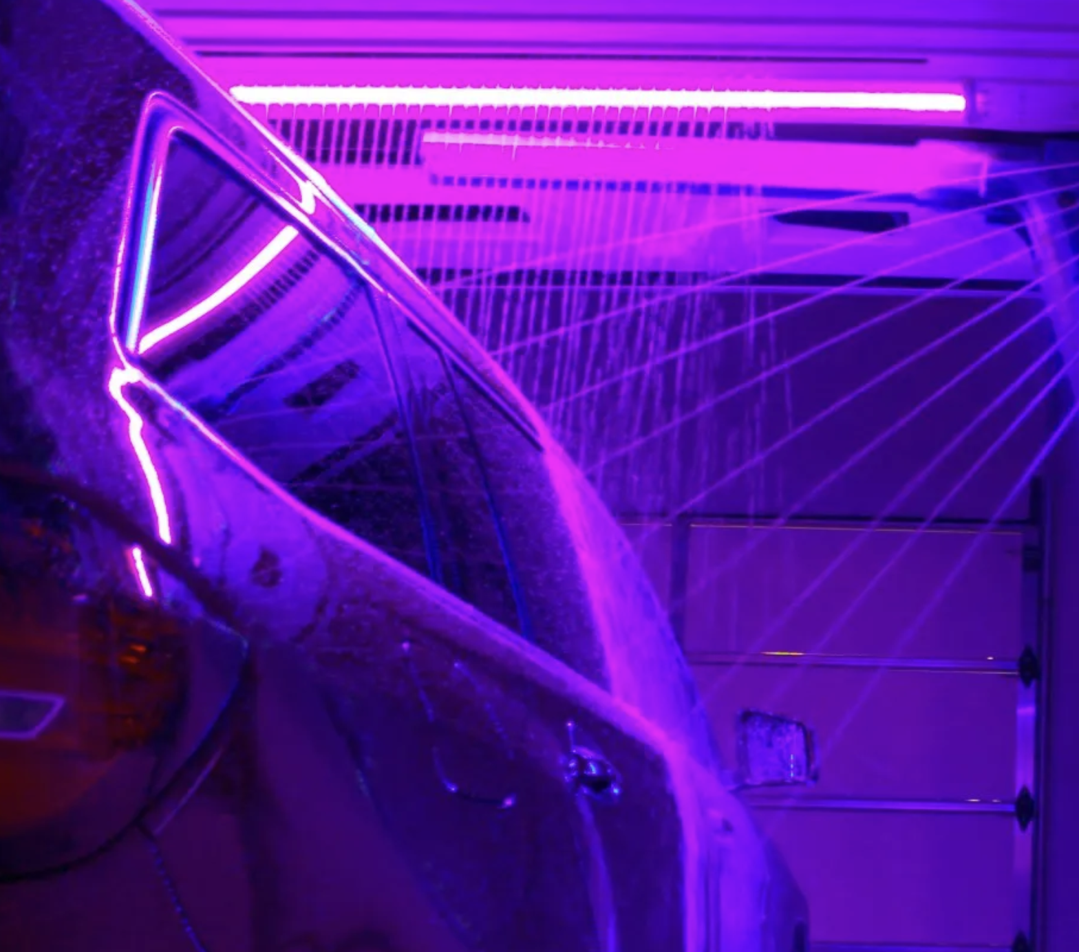 A car covered in snow is illuminated by purple neon lights, with a garage door in the background.