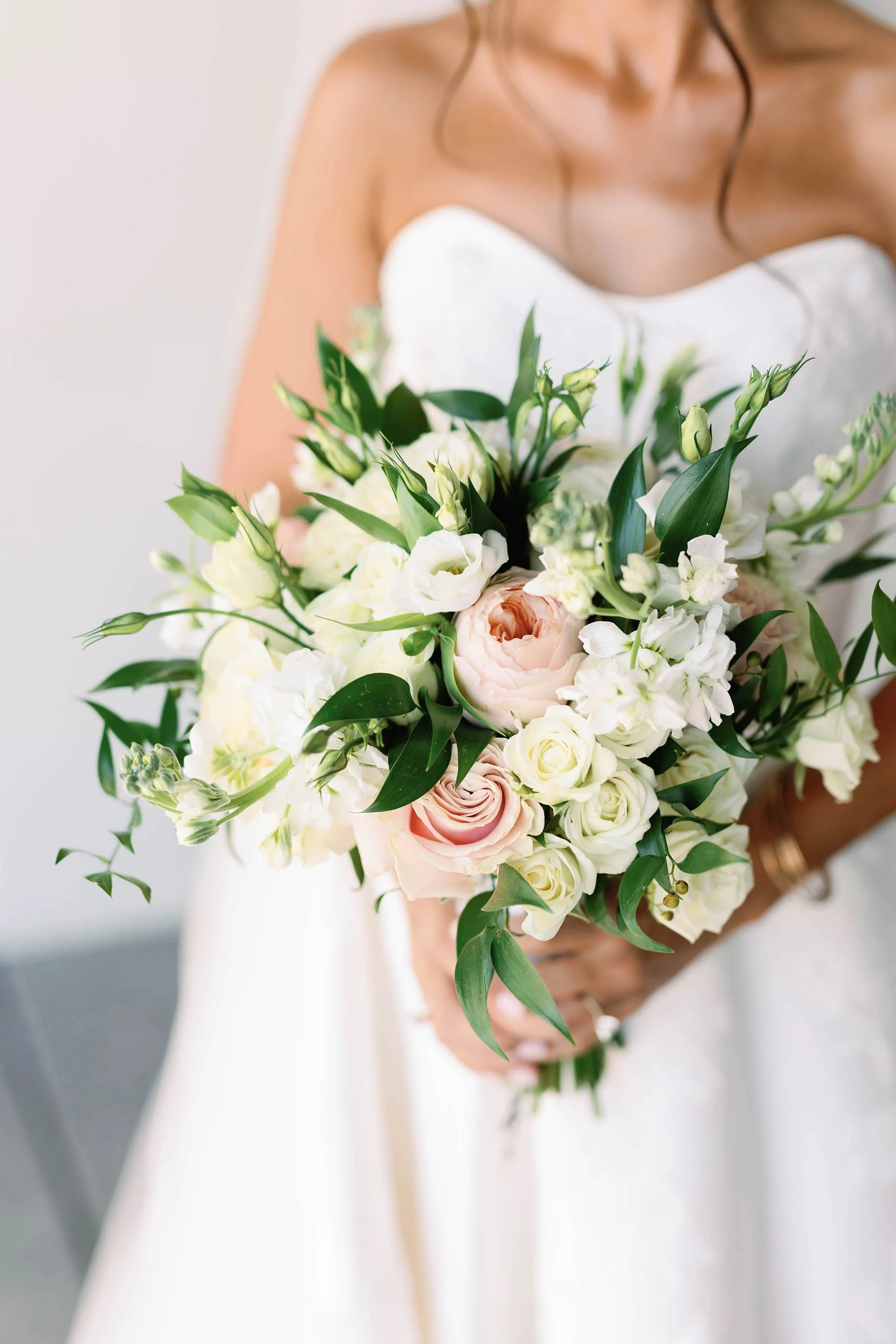A bride holding a bouquet of white and pale pink flowers.