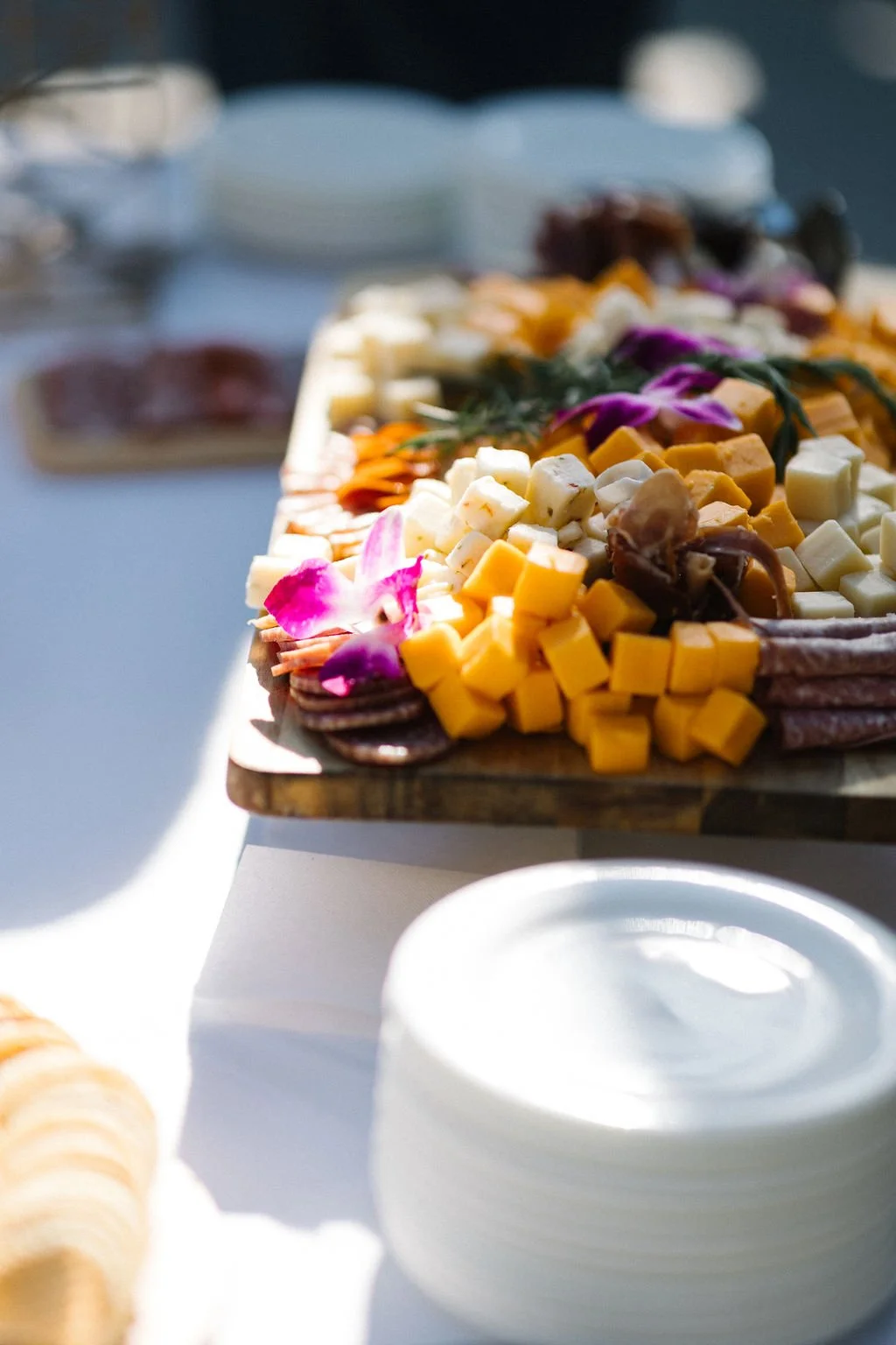 Cheese and charcuterie platter with flower garnishes on a wooden board