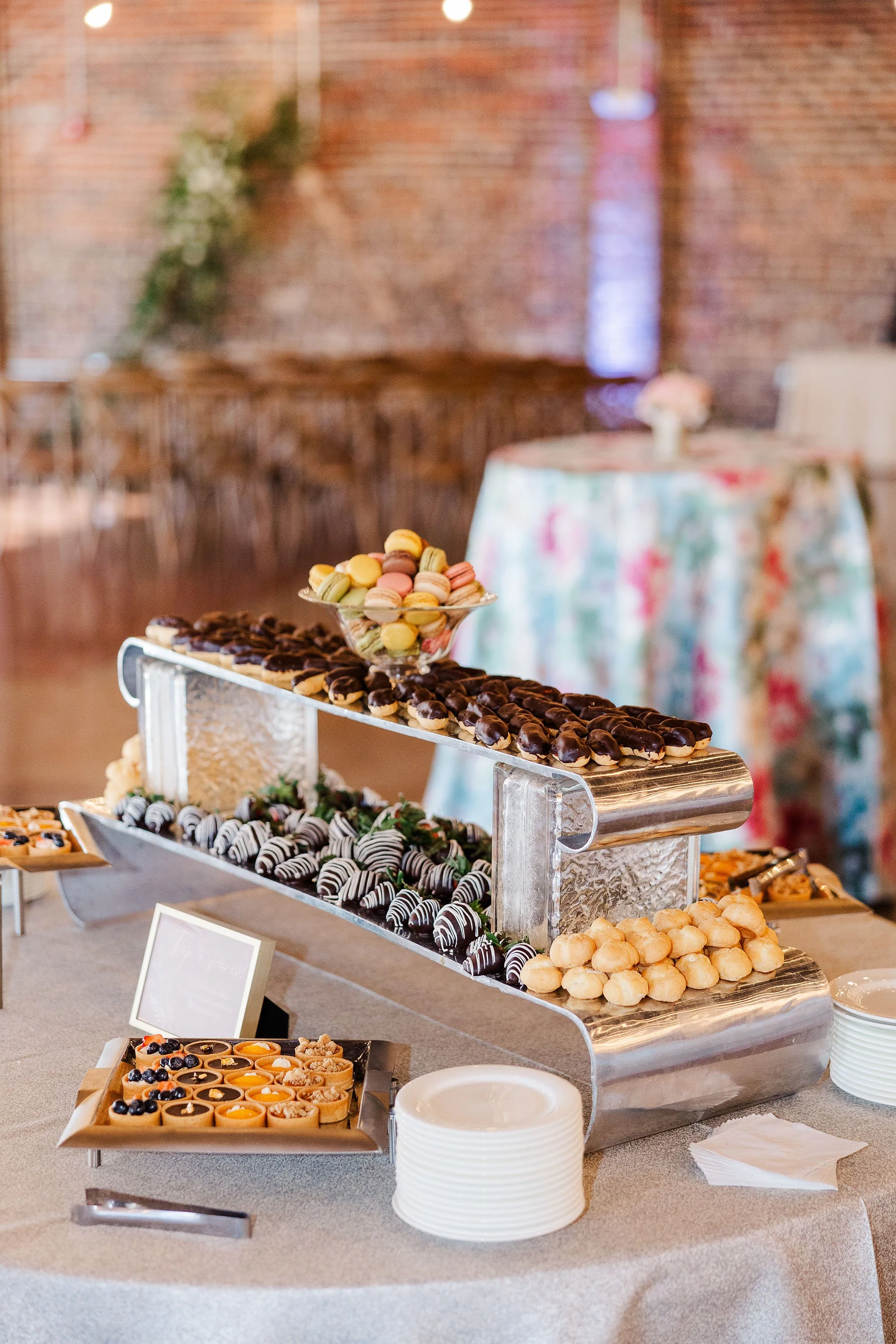 Dessert table with macarons, chocolate-covered treats, berries, and small pastries at a celebration event.