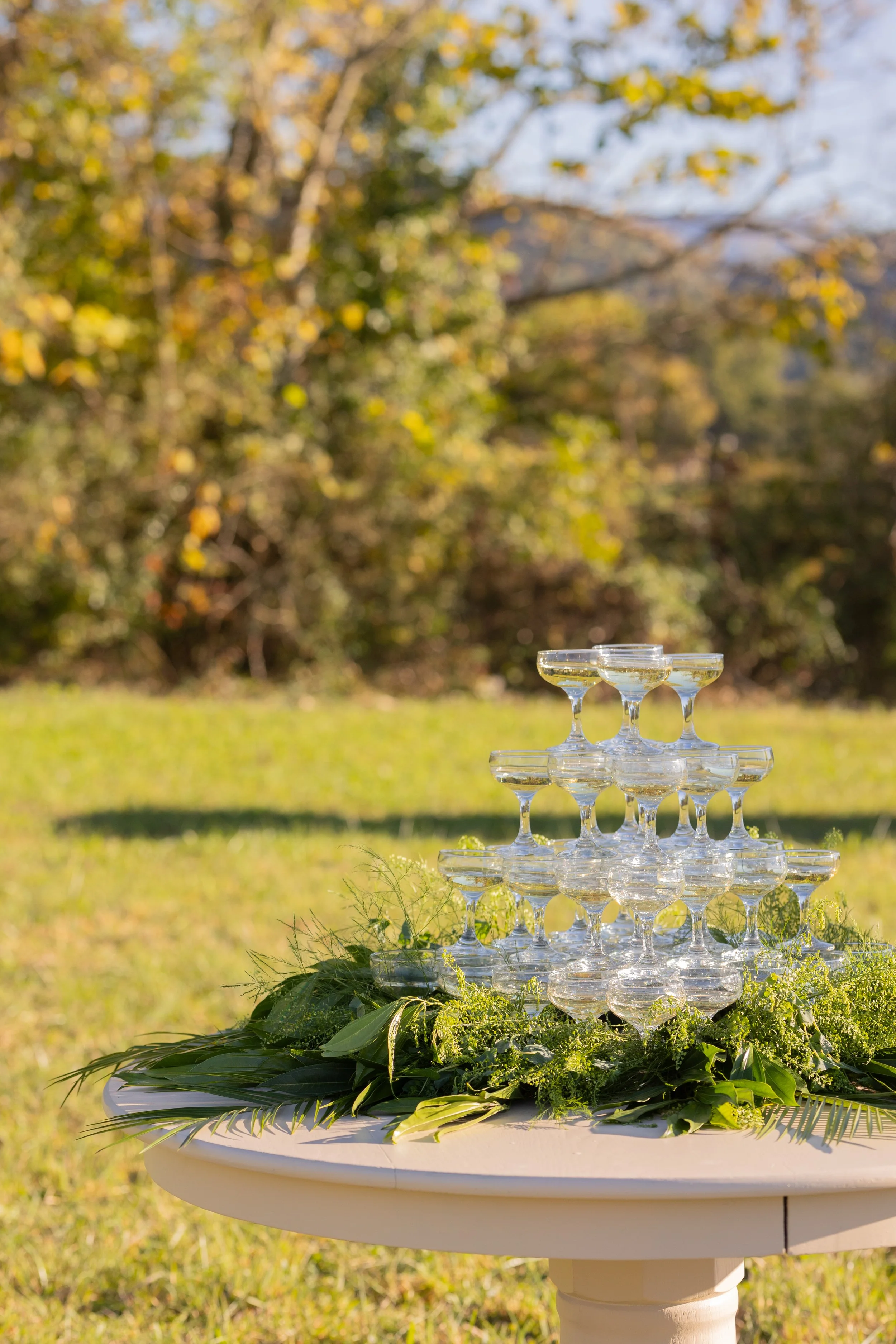 Champagne tower styled with fresh greenery and mountain views at The Lumigail wedding venue in the Smoky Mountains.