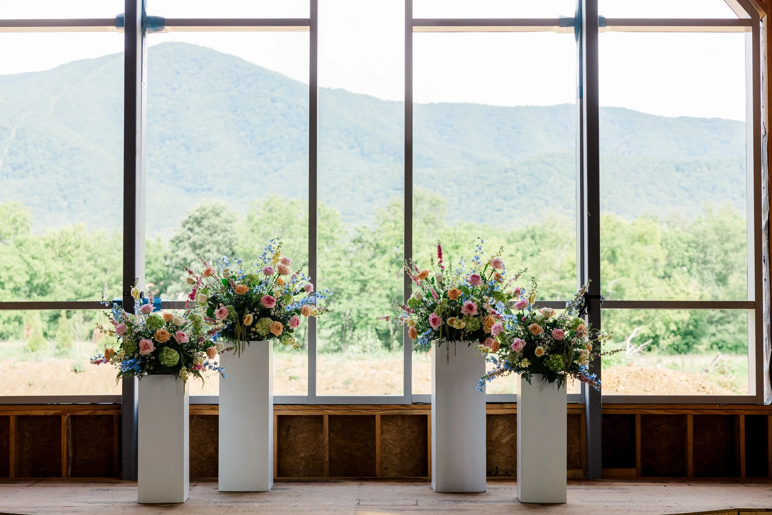 Colorful floral arrangements inside The Lumigail chapel framed by floor-to-ceiling windows with sweeping Smoky Mountain views near Pigeon Forge, Tennessee.