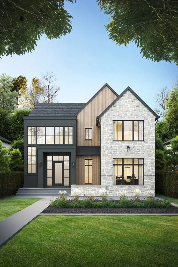 Modern two-story house with a combination of stone and wood exterior, large windows, and a front porch, surrounded by green grass and trees.
